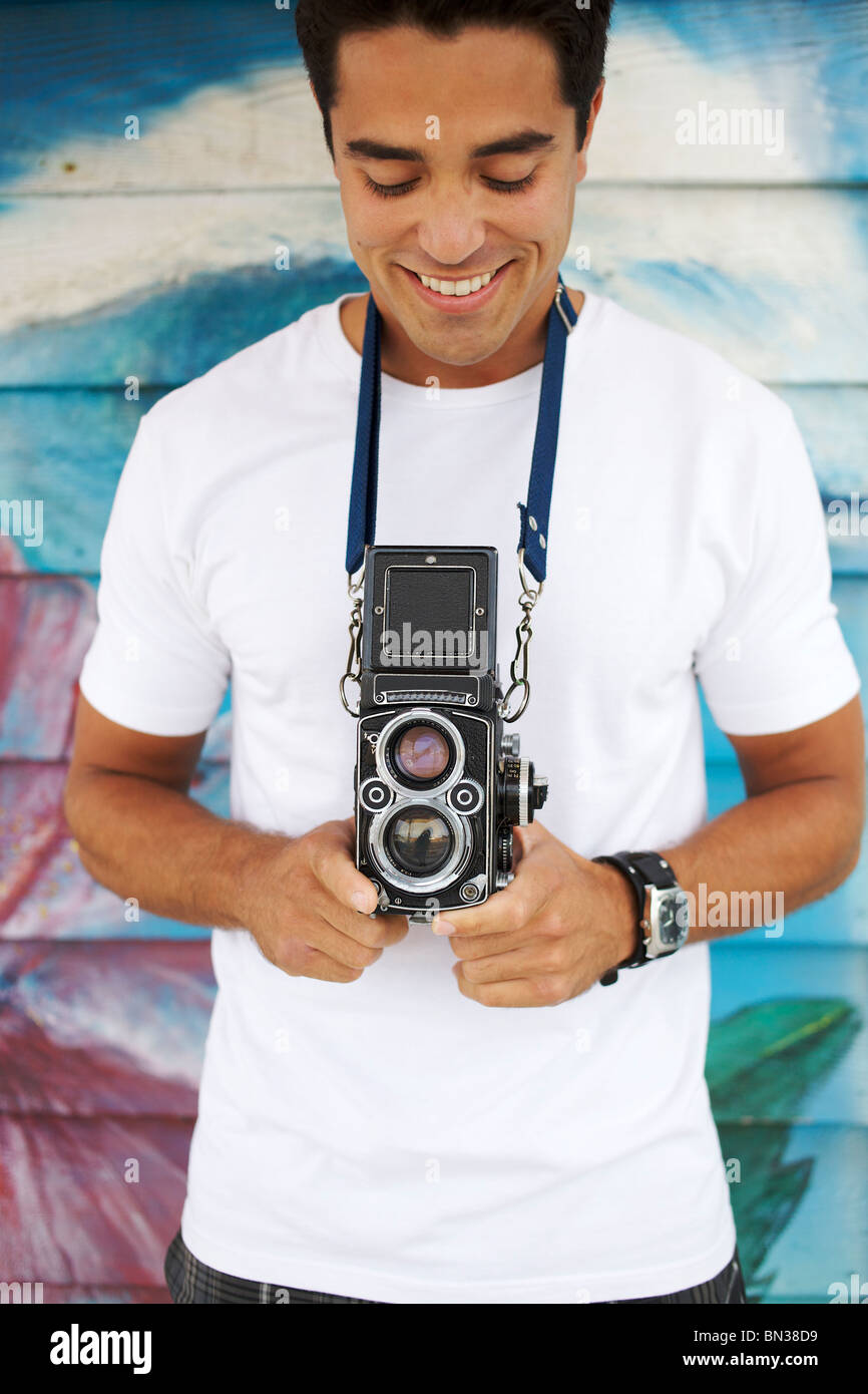 Mixed race man holding old-fashioned camera Stock Photo