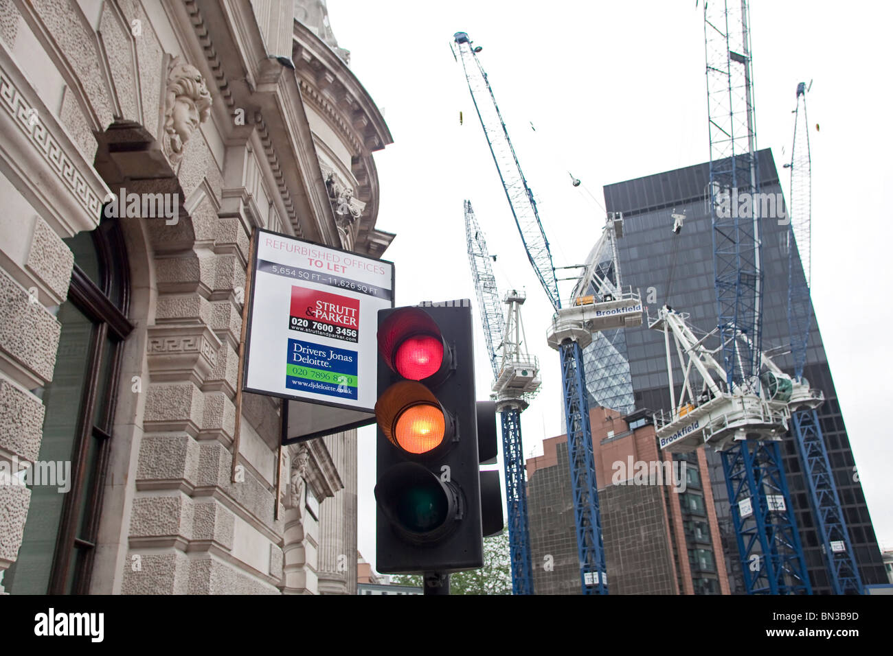 Offices to let, red traffic lights and at the back a construction site for a new office building in London Stock Photo