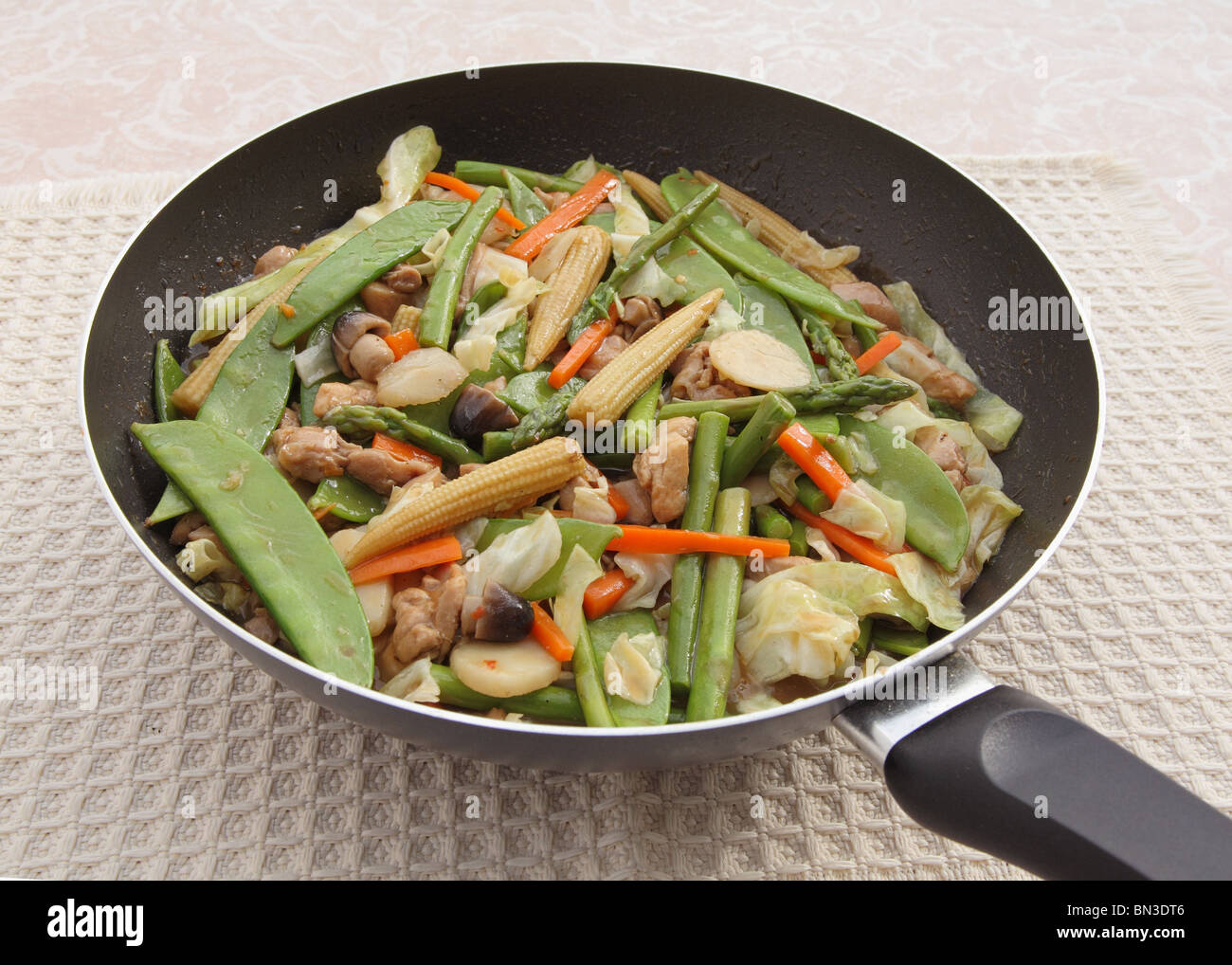 wok pan full of chicken vegetable stir-fry Stock Photo