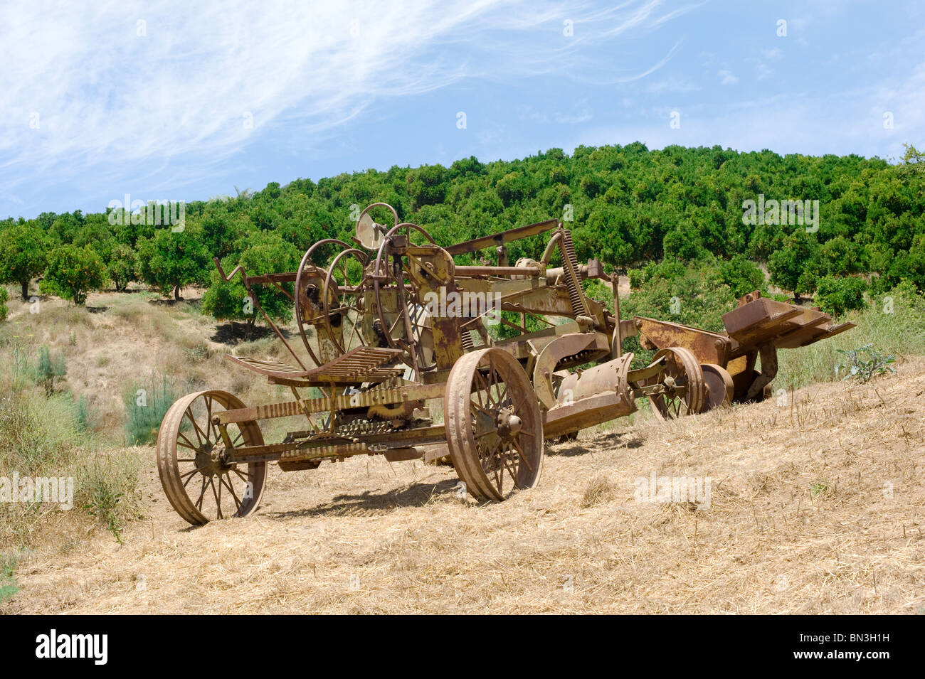 Old farming equipment in a remote field including a tractor and a hoe. Stock Photo