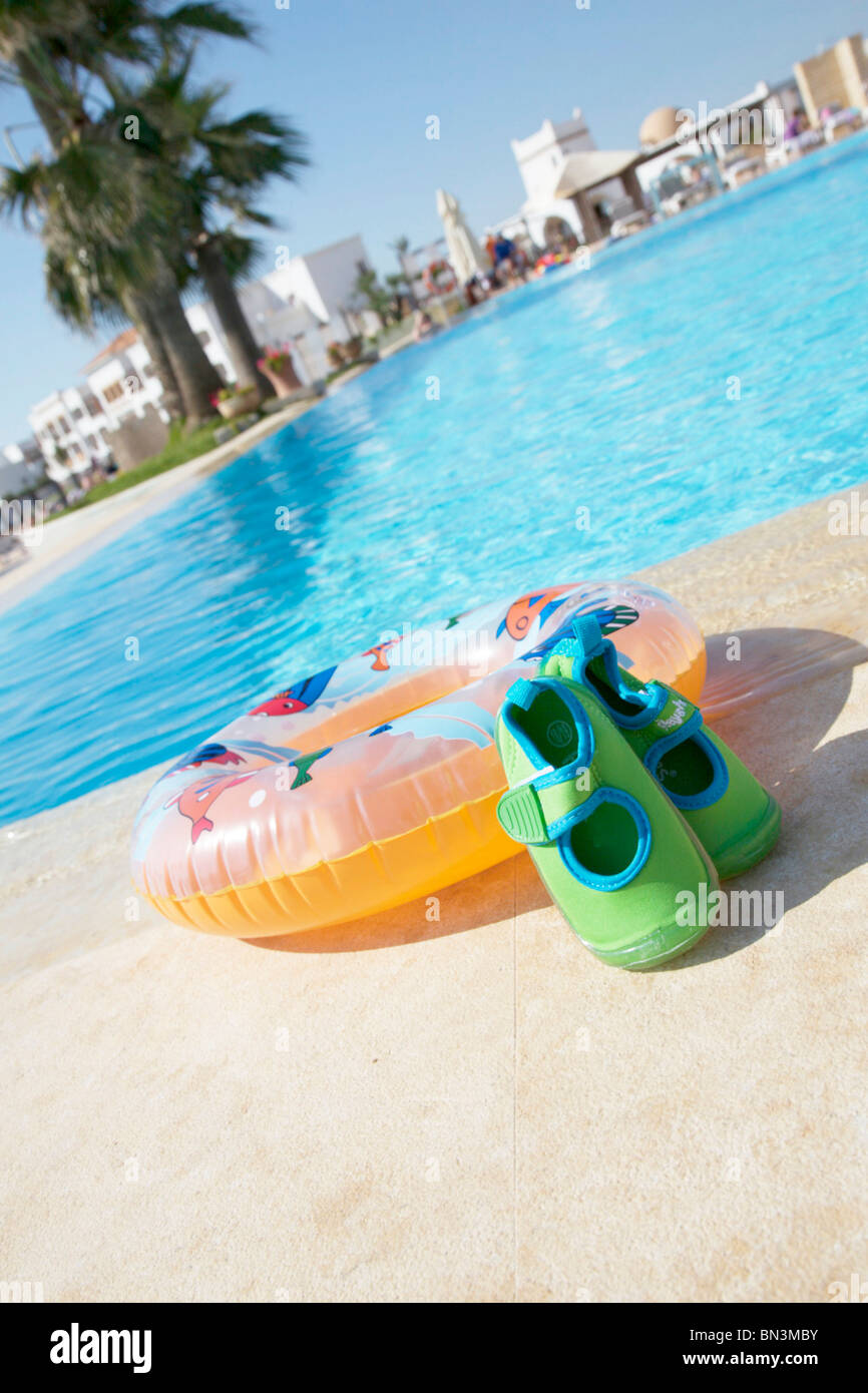 Bathing shoes and inflatable ring by pool side, slanted Stock Photo