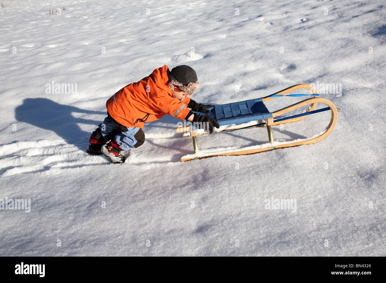 Child pushing a sledge on the snow, Jerzens, Austria Stock Photo