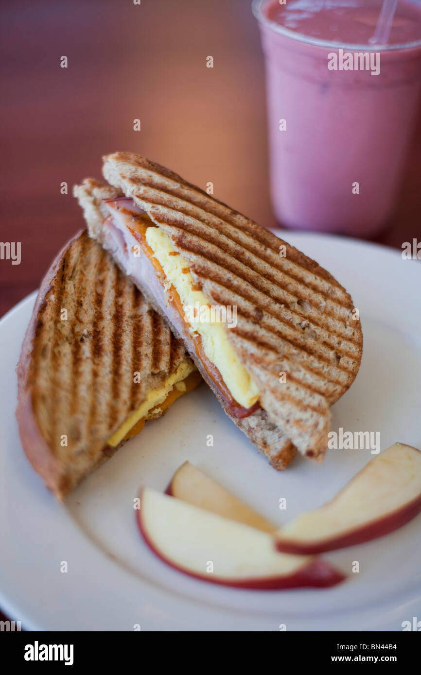 Ham, egg and cheese panino with wheat bread and a side of apples. Shown with a berry fruit smoothie. Shot at The Grind in Biloxi Stock Photo