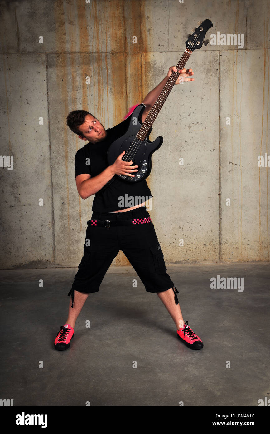 Man playing bass guitar in industrial grunge environment Stock Photo