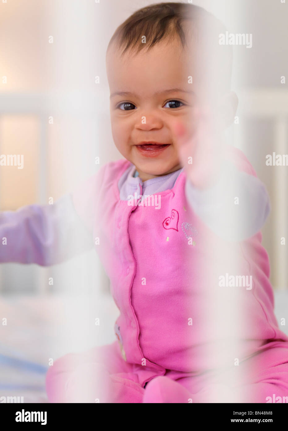 Cute seven month old smiling baby girl sitting inside a crib Stock Photo Alamy
