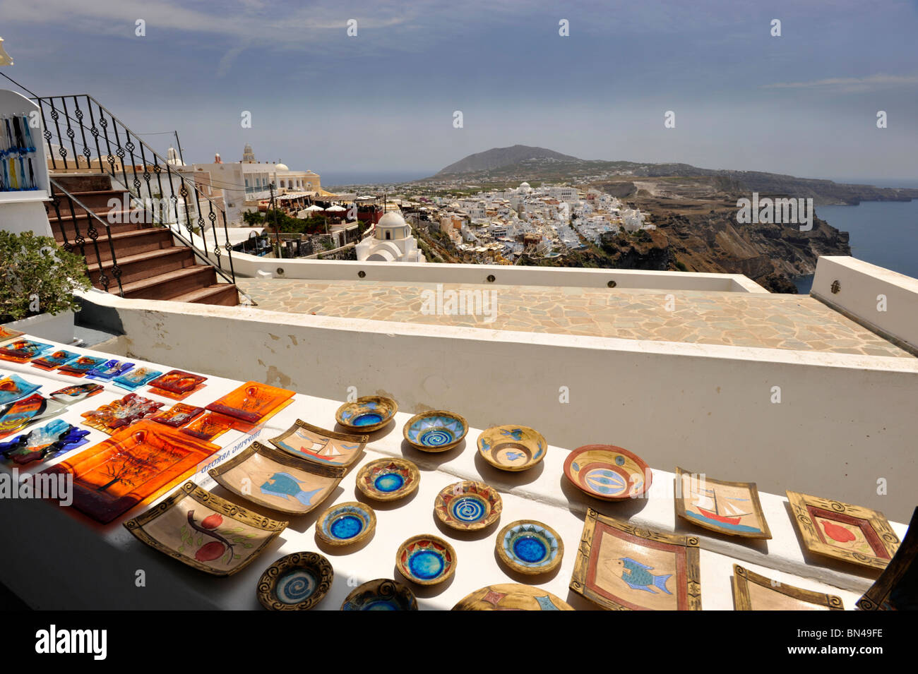 Glass and ceramic Tourist Souvenirs in Santorini with the capital Fira on the horizon Stock Photo