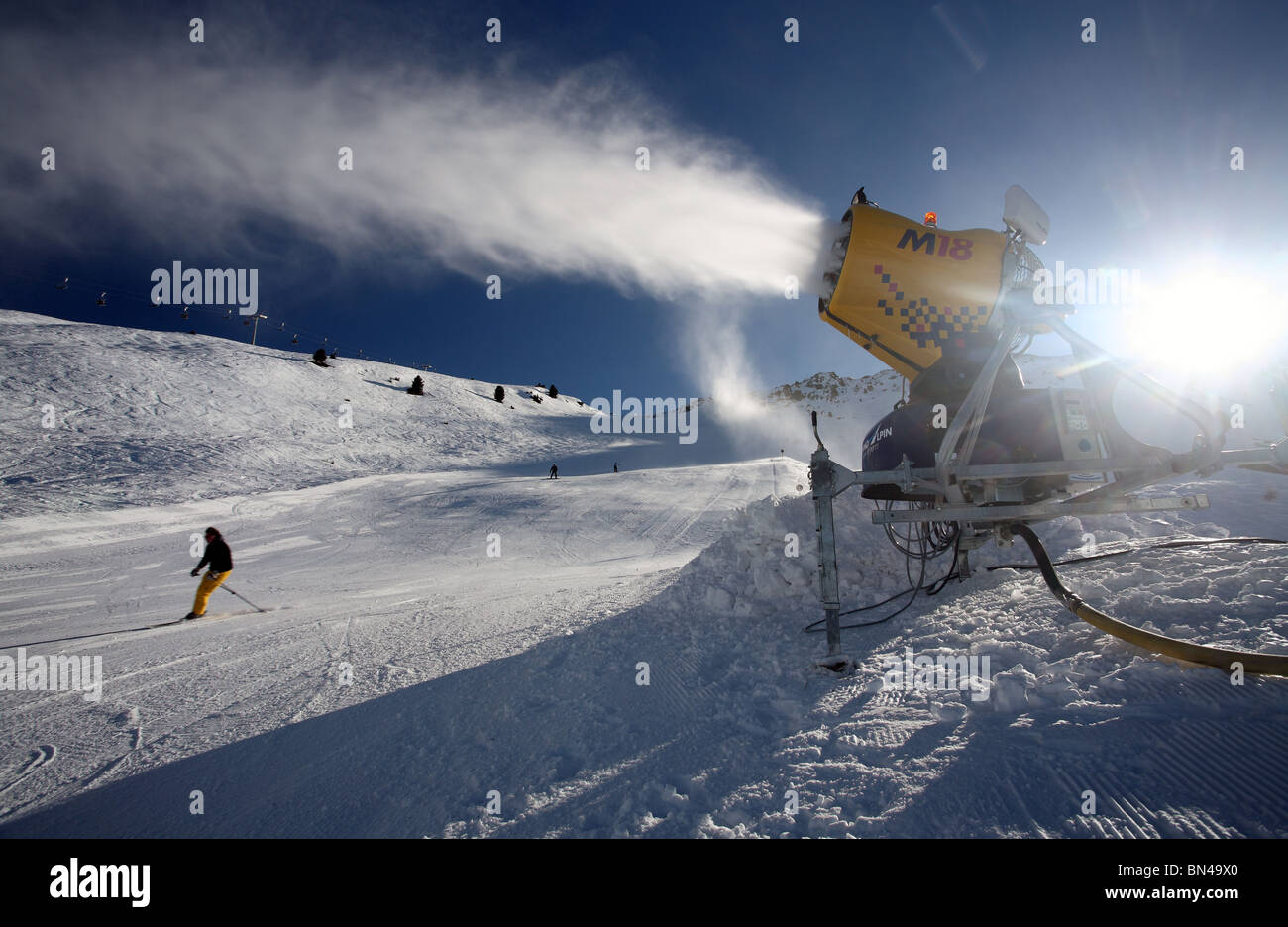 A snow cannon and skiers on the slope, Jerzens, Austria Stock Photo