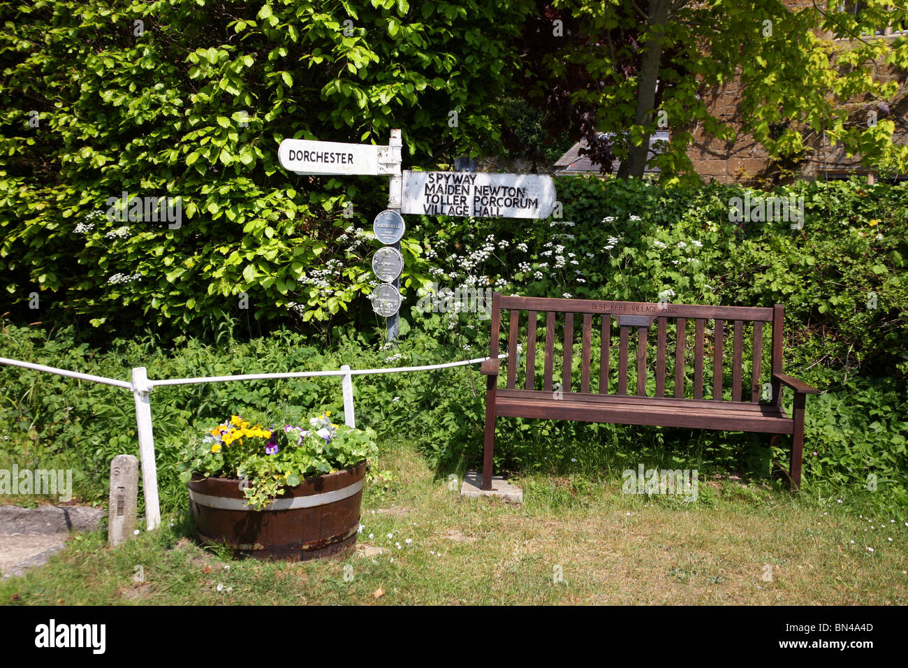 Signpost and seat at crossroads in the centre of Askerswell,  a picturesque West Dorset village near Bridport Stock Photo