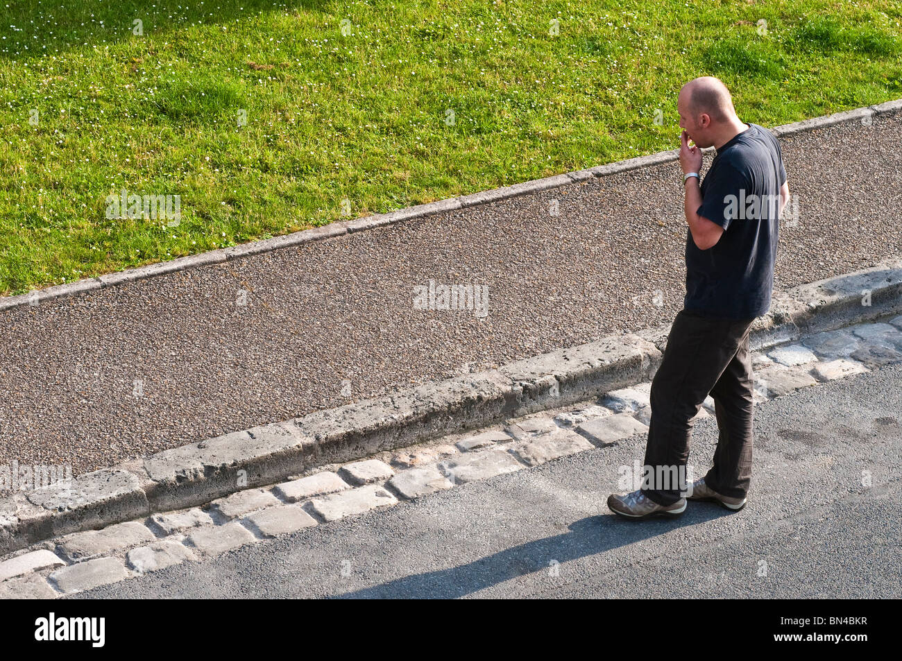 Man stood smoking at side of road - France. Stock Photo