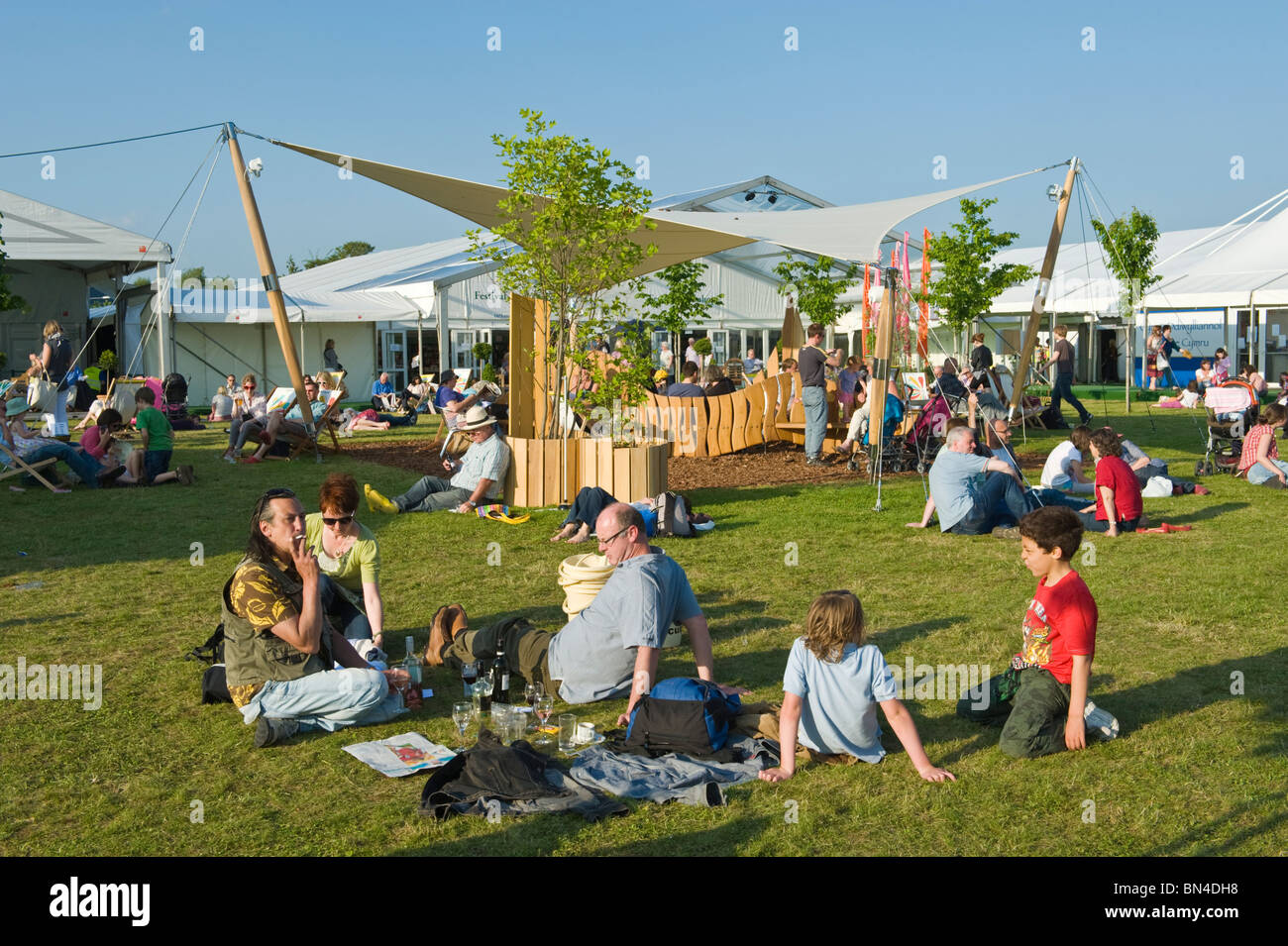 People relaxing sitting on grass in the summer sunshine at Hay Festival 2010 Hay on Wye Powys Wales UK Stock Photo