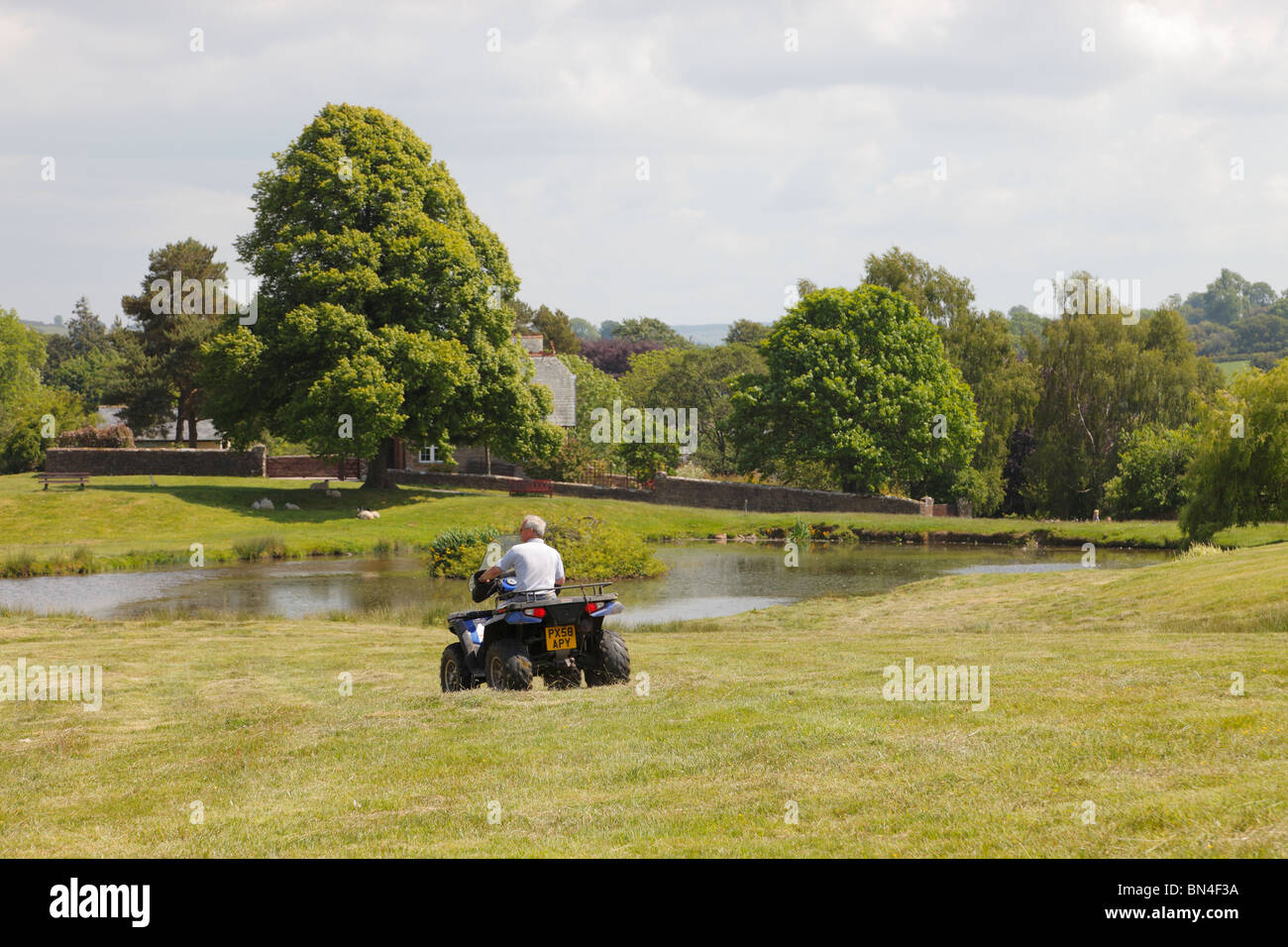 Farmer on quadbike. Duck Pond Caldbeck, The Lake District Cumbria sunny summers day with blue sky and white clouds. Stock Photo