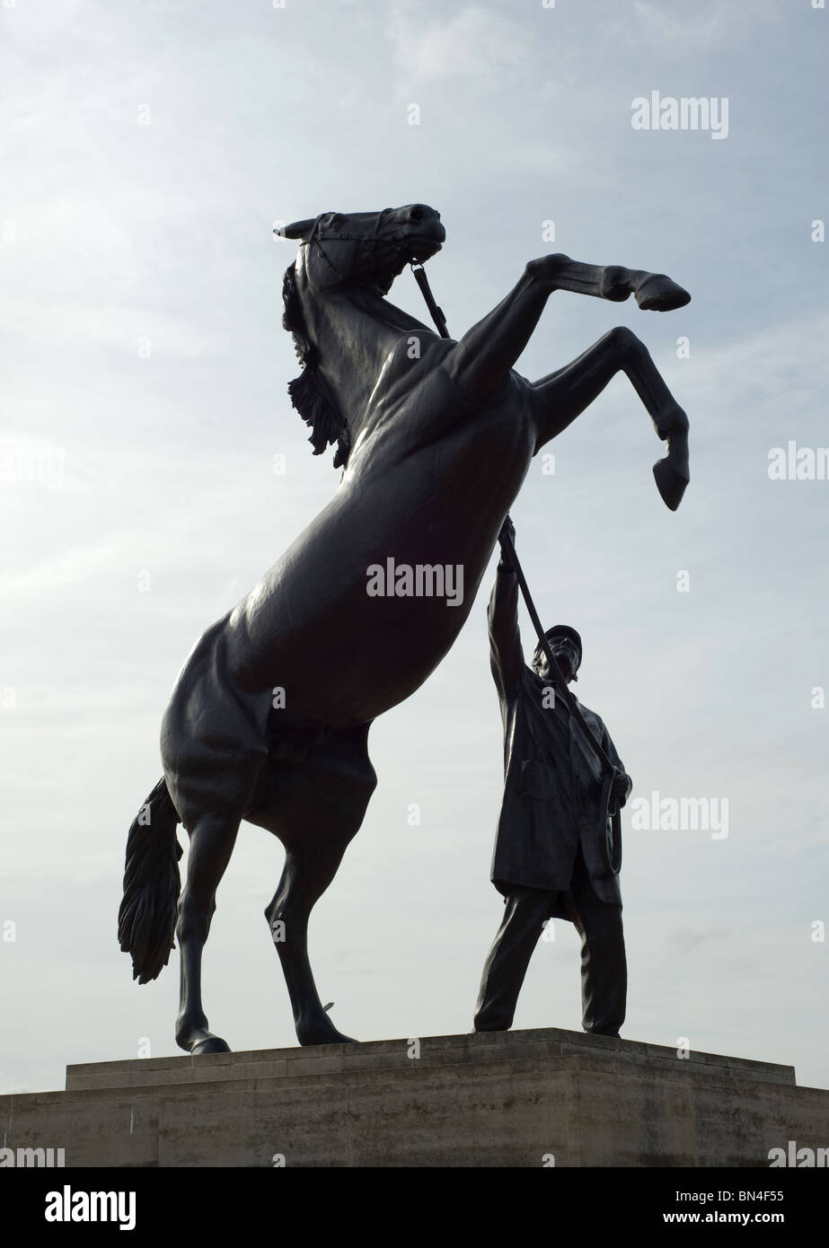 A black statue of a horse standing on it's hind legs rearing up with its handler holding the reins. Photo by Matt Kirwan. Stock Photo