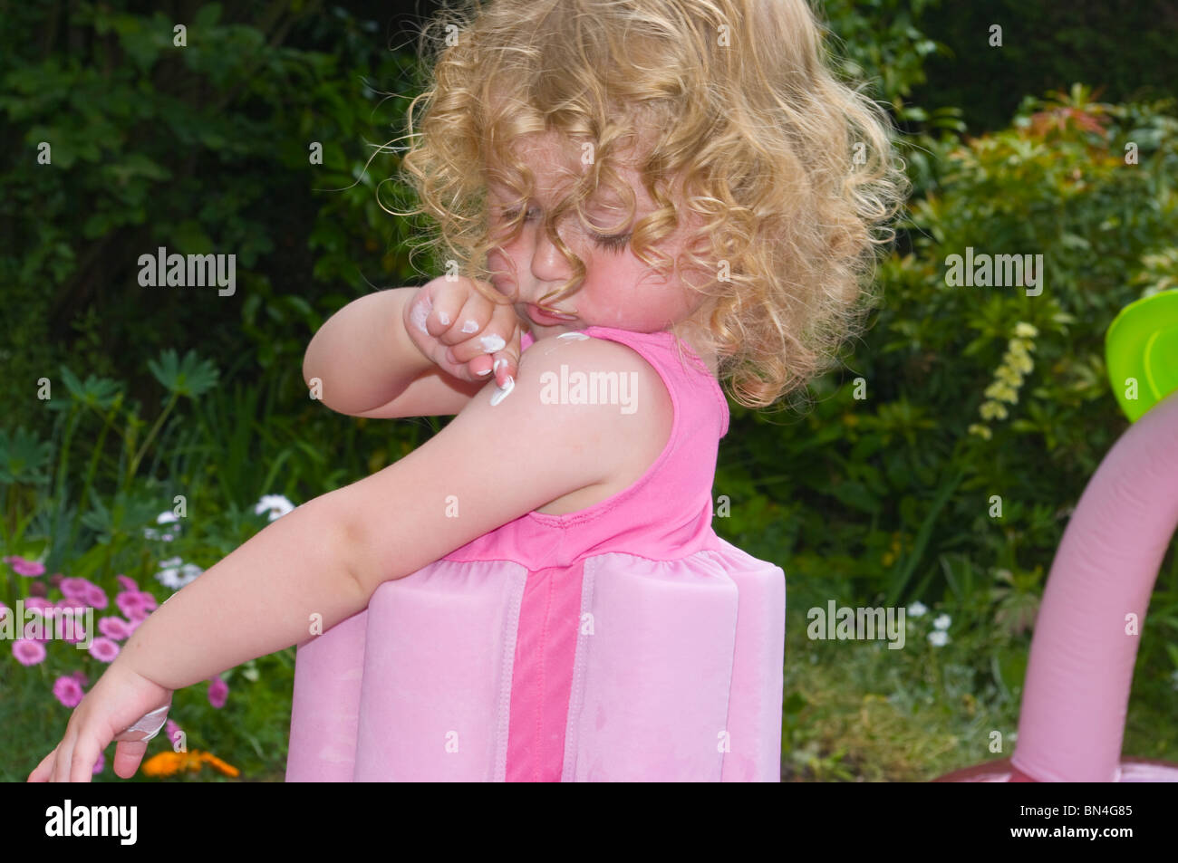 2 Year Old Girl Applying Suncream To Her Arm Stock Photo