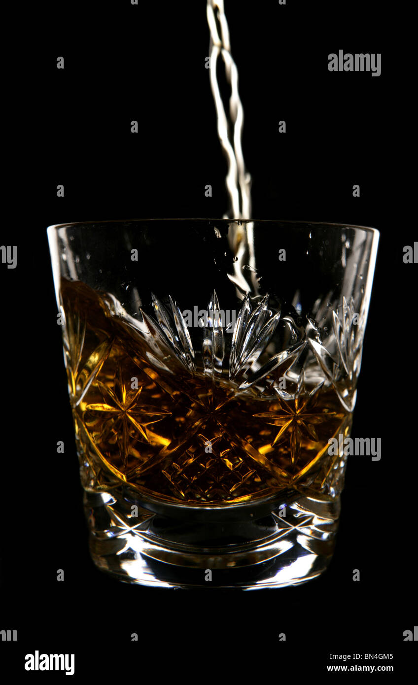 Whiskey being poured in crystal glass in studio Stock Photo