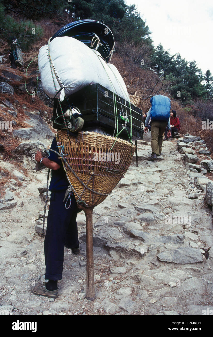 Porter with his load approaches Namche Bazar; Solo Khumbu district; Everest region; Nepal Stock Photo