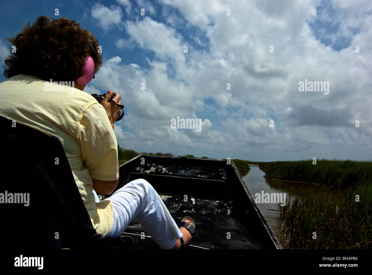 Woman photographing during airboat tour of Louisiana saltwater bayou marshland sloughs in Grand Chenier LA Stock Photo