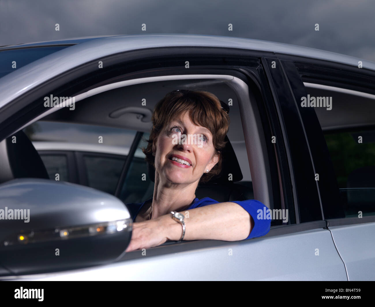 Confident older woman,in her car, looks hopefully skywards. Stock Photo