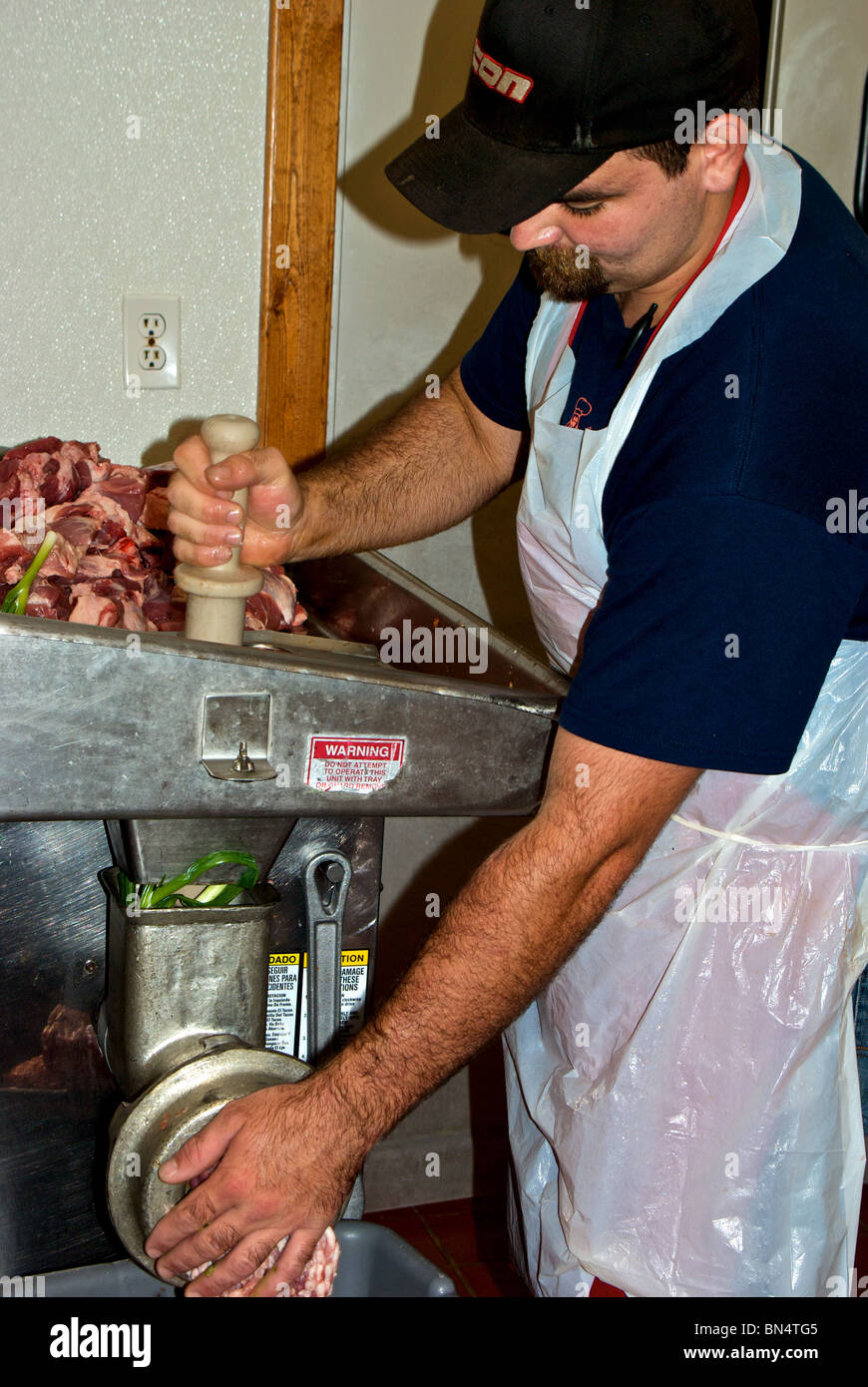 Worker grinding fresh raw pork green onions to make filling for boudin