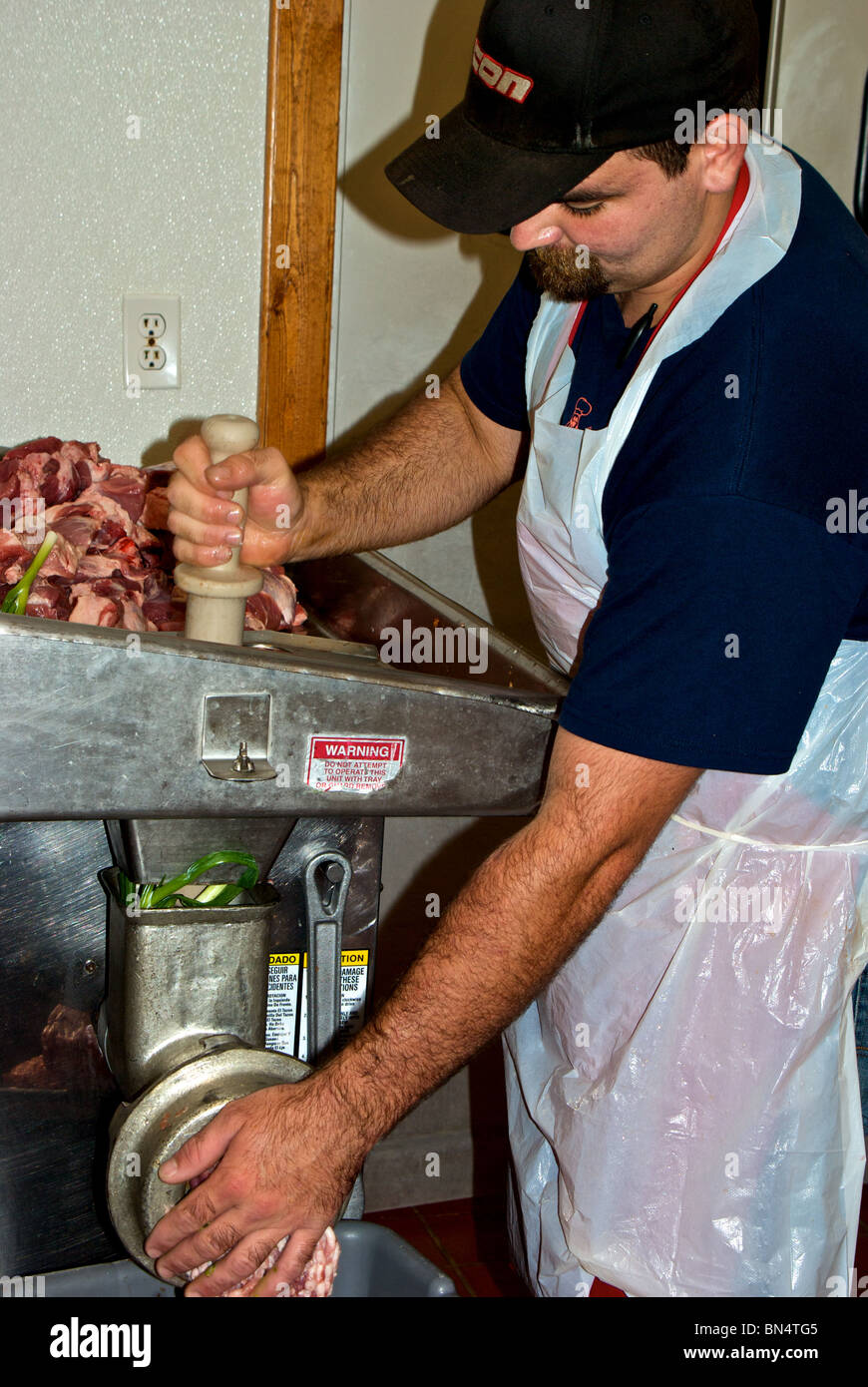 Worker grinding fresh raw pork green onions to make filling for boudin sausage at The Sausage Link in Sulphur LA Stock Photo