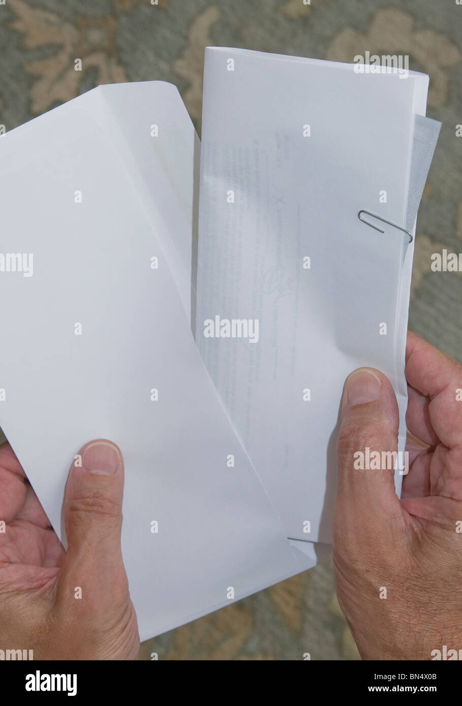 closeup of hands placing document and check in envelope Stock Photo