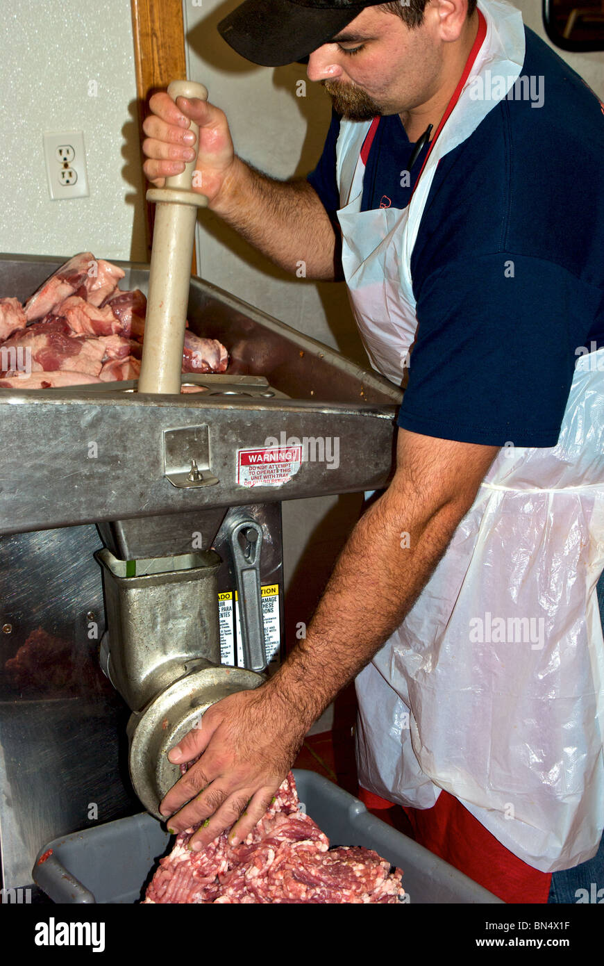 Worker grinding fresh raw pork green onions to make filling for boudin sausage at The Sausage Link in Sulphur LA Stock Photo