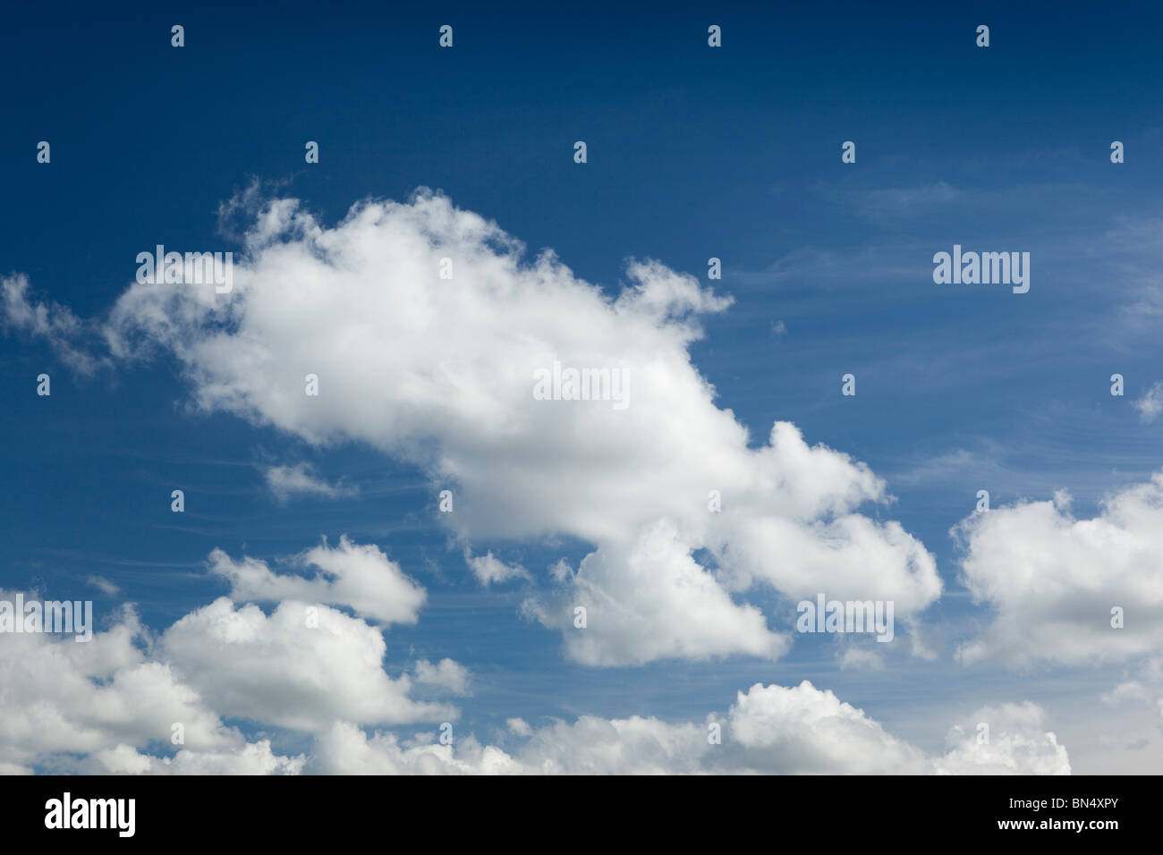 Weather small fluffy white cumulus clouds below cirrus in blue sky on summer’s day Stock Photo