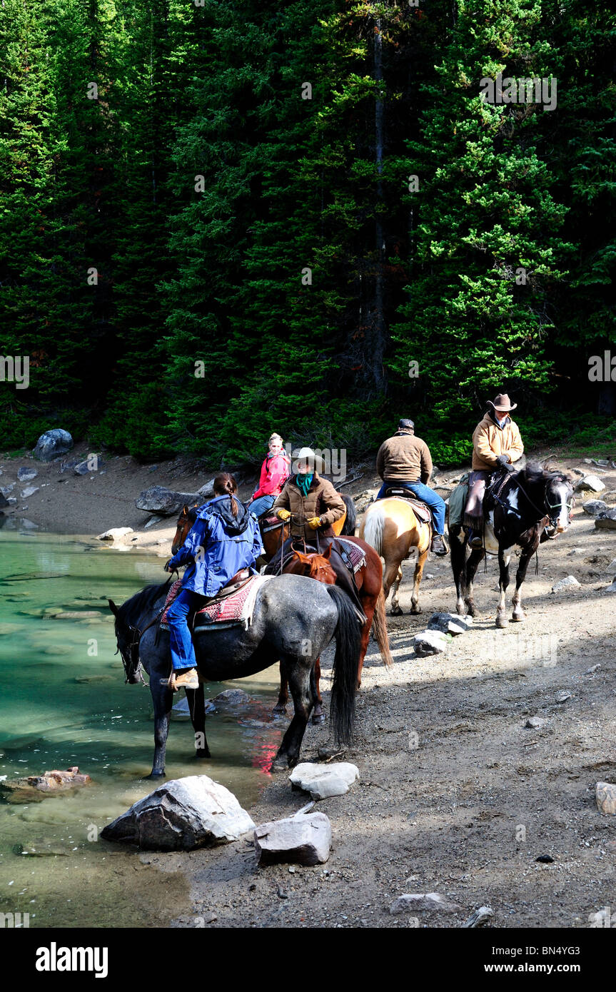 Trail riders water their horses by a lake. Banff National Park, Alberta, Canada. Stock Photo