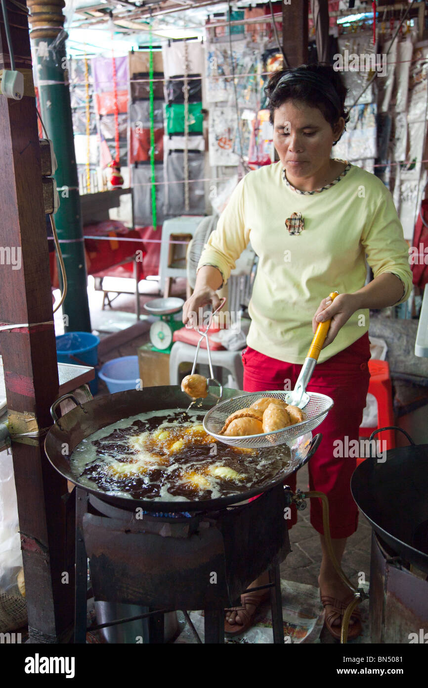 A street hawker fries curry puffs in a wok in a street market in Kuala Lampur, Malaysia Stock Photo