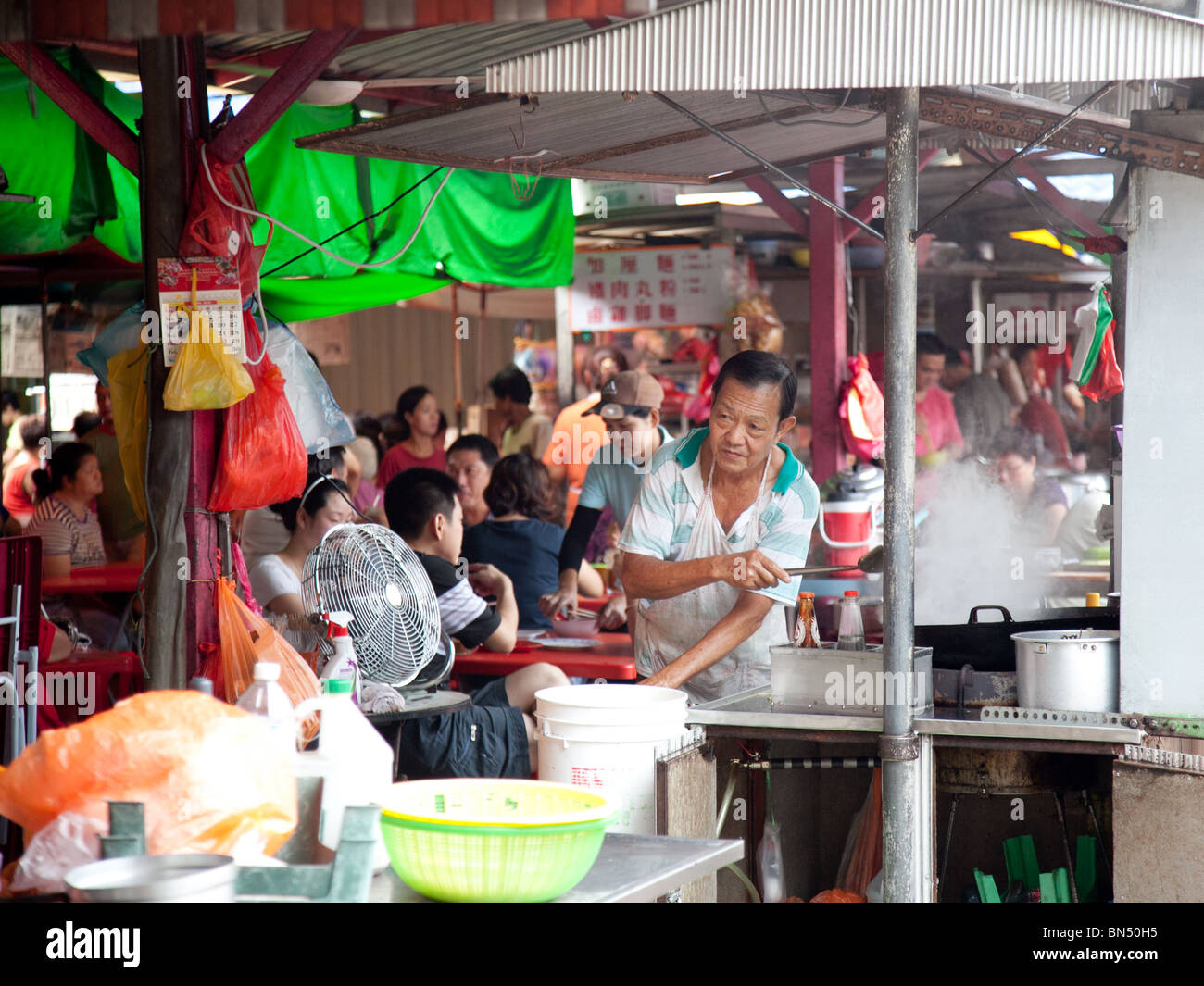 A street Hawker in the Imbi Road Chinese Market in Kuala Lampur Malaysia cooks Char Kuey Teow -  noodles with cockles Stock Photo
