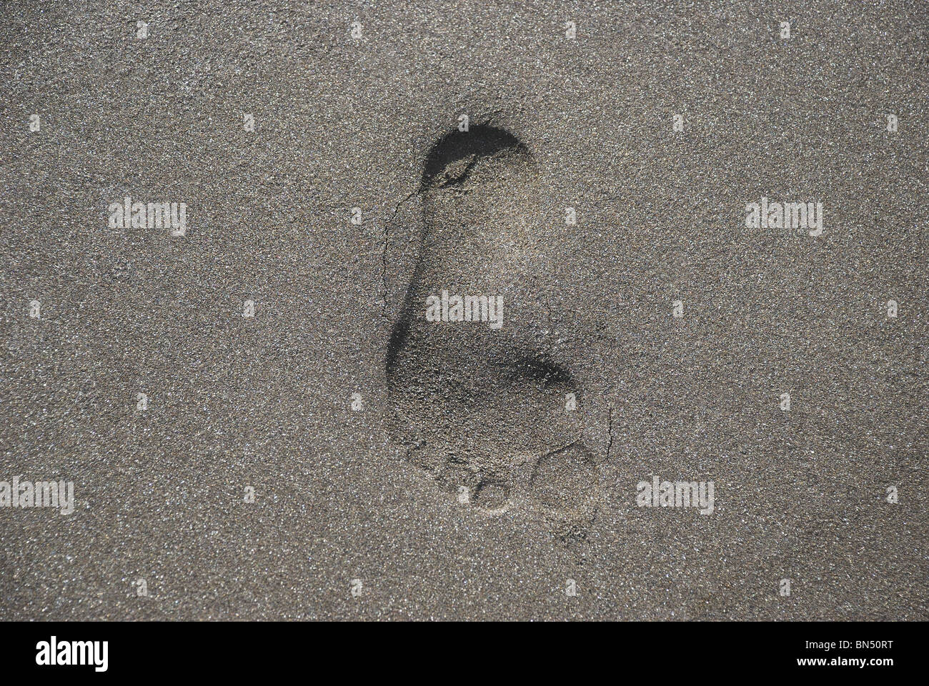An impression of a human foot engraved in wet sea sand Stock Photo