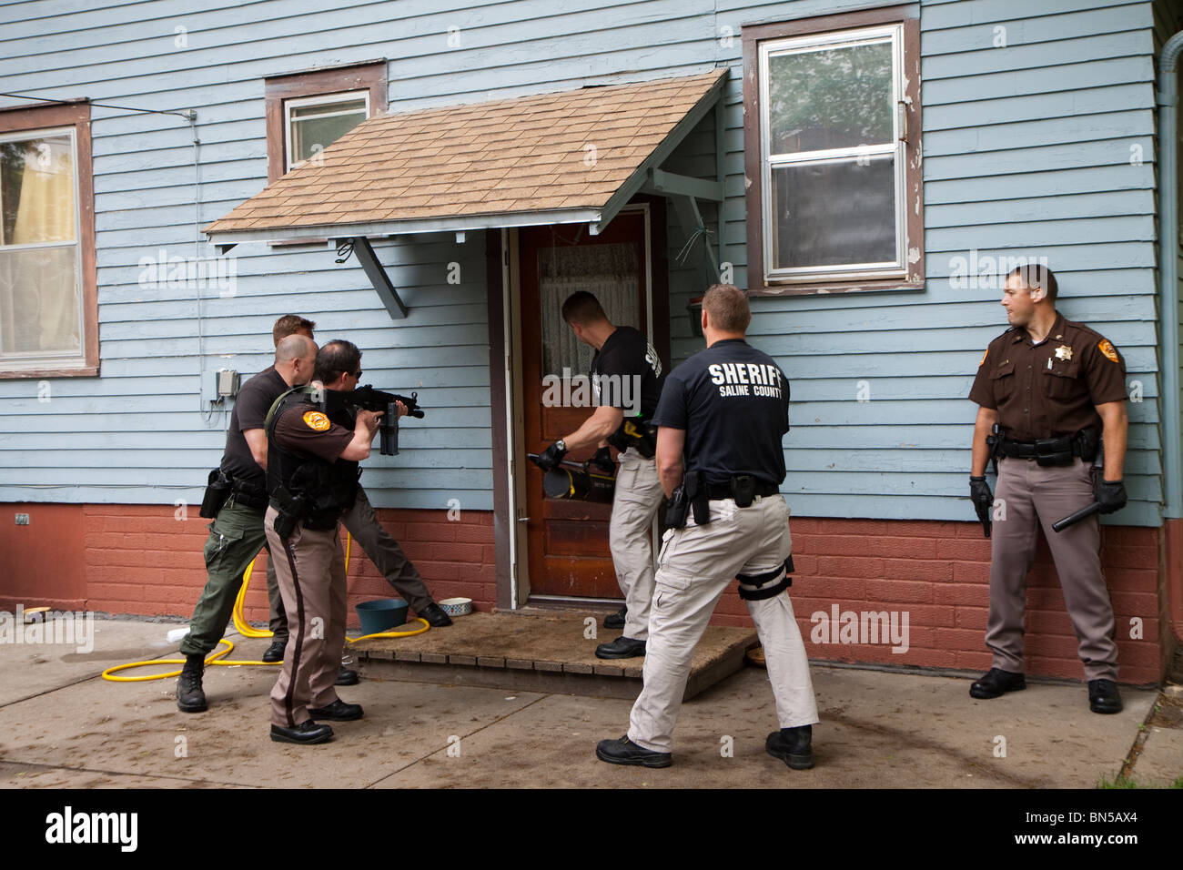 Deputy sheriff's serving drug related search warrant in a rural US community. Narcotics were located inside the residence. Stock Photo
