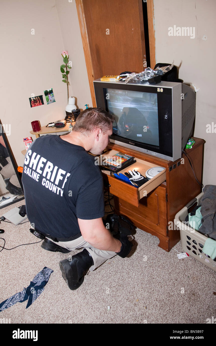 Sheriff deputy searching for illegal narcotics during execution of search warrant in rural city. Saline County Sheriff, Nebraska Stock Photo