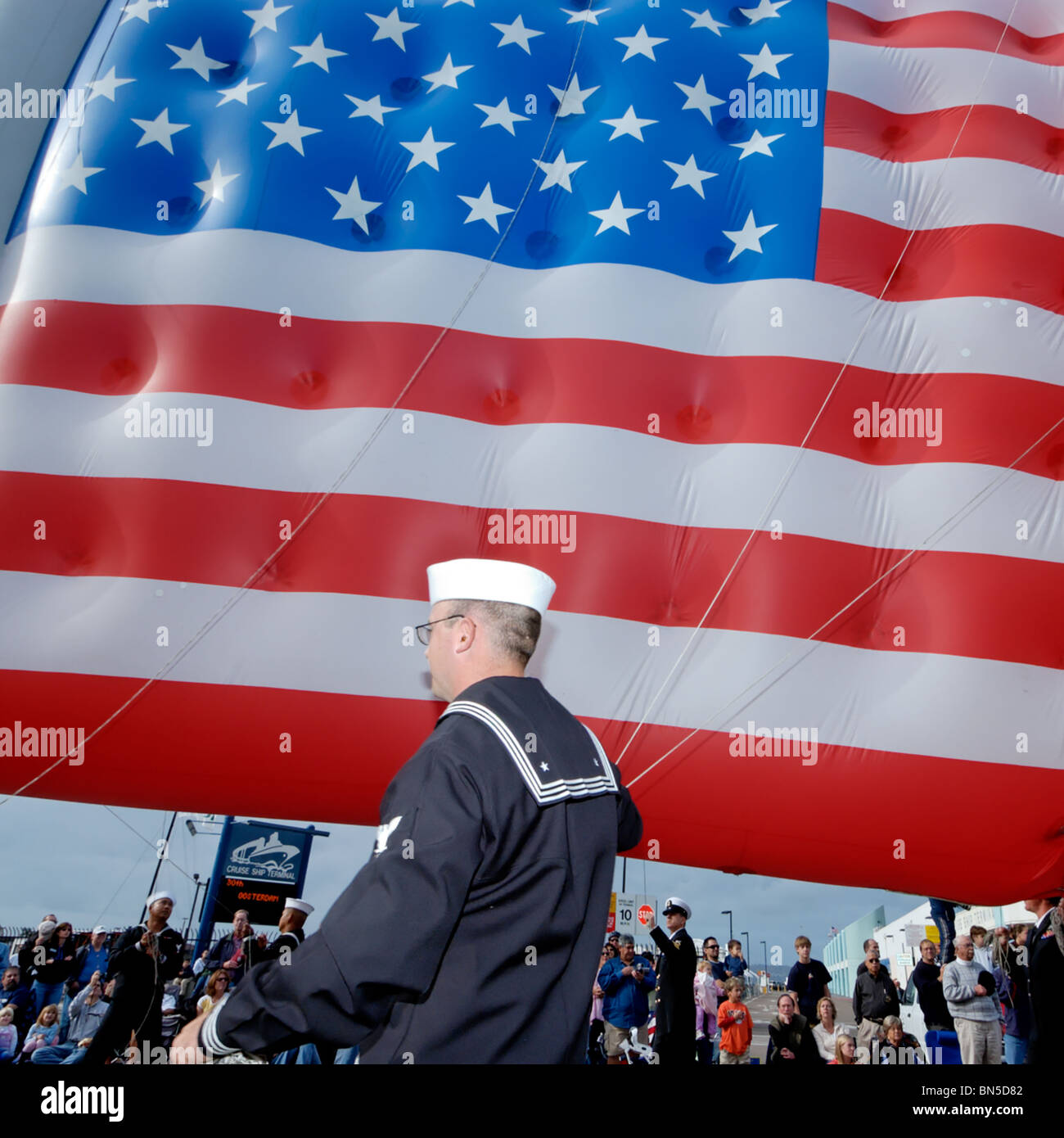 Sailor with American flag balloon preparing for Big Bay Balloon Parade San Diego California USA - Stock Image