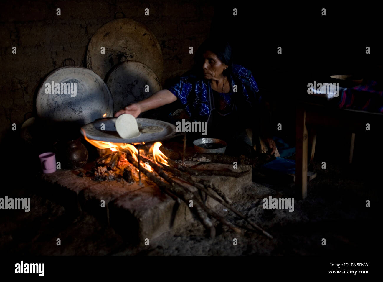 A Mayan Tzotzil woman makes corn tortillas for tourists in her souvenir shop in Zinacantan, Chiapas, Mexico. Stock Photo