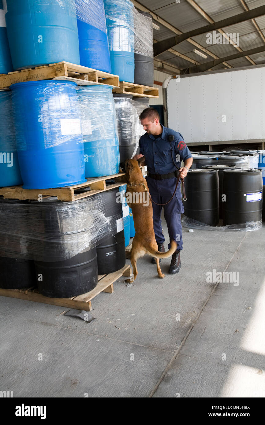 Corrections Officer dog handler with K-9 searching boxes in prison warehouse. Nebraska State Penitentiary. Stock Photo