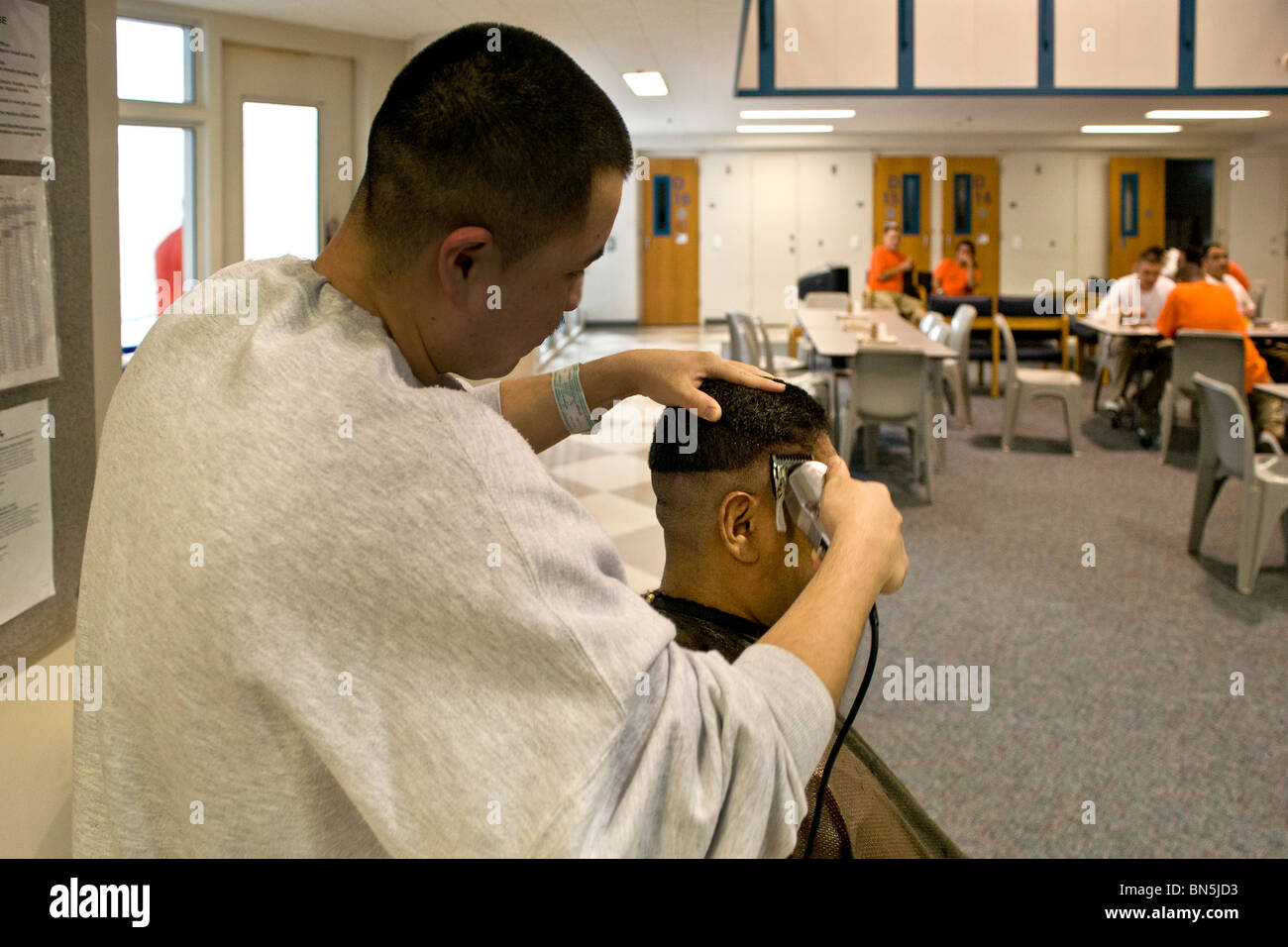 A Hispanic inmate gets a haircut in the dayroom of a cell block at the Santa Ana, CA, city jail. Stock Photo