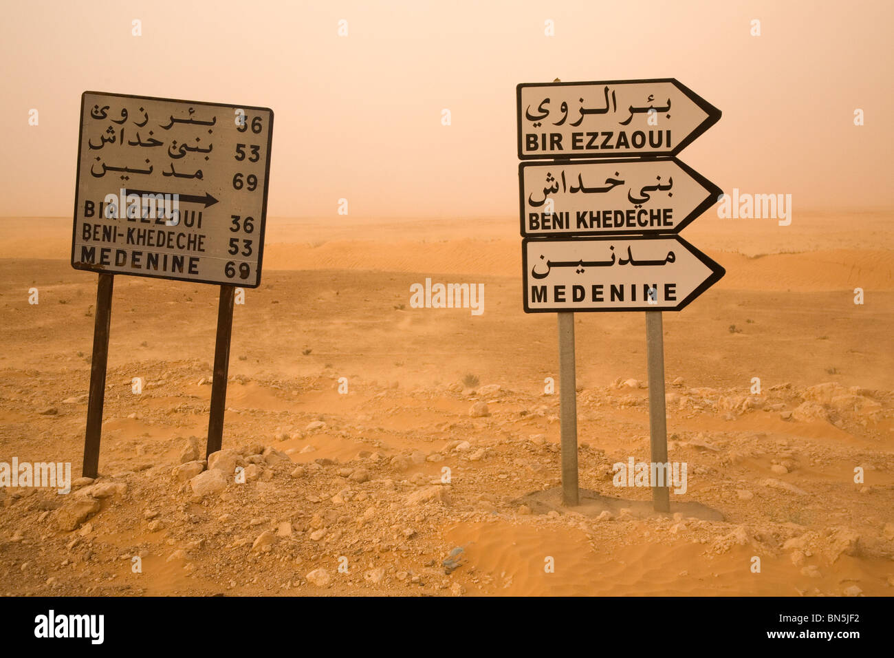 Road signs in the Sahara Desert are written with Arabic and Latin letters. Stock Photo