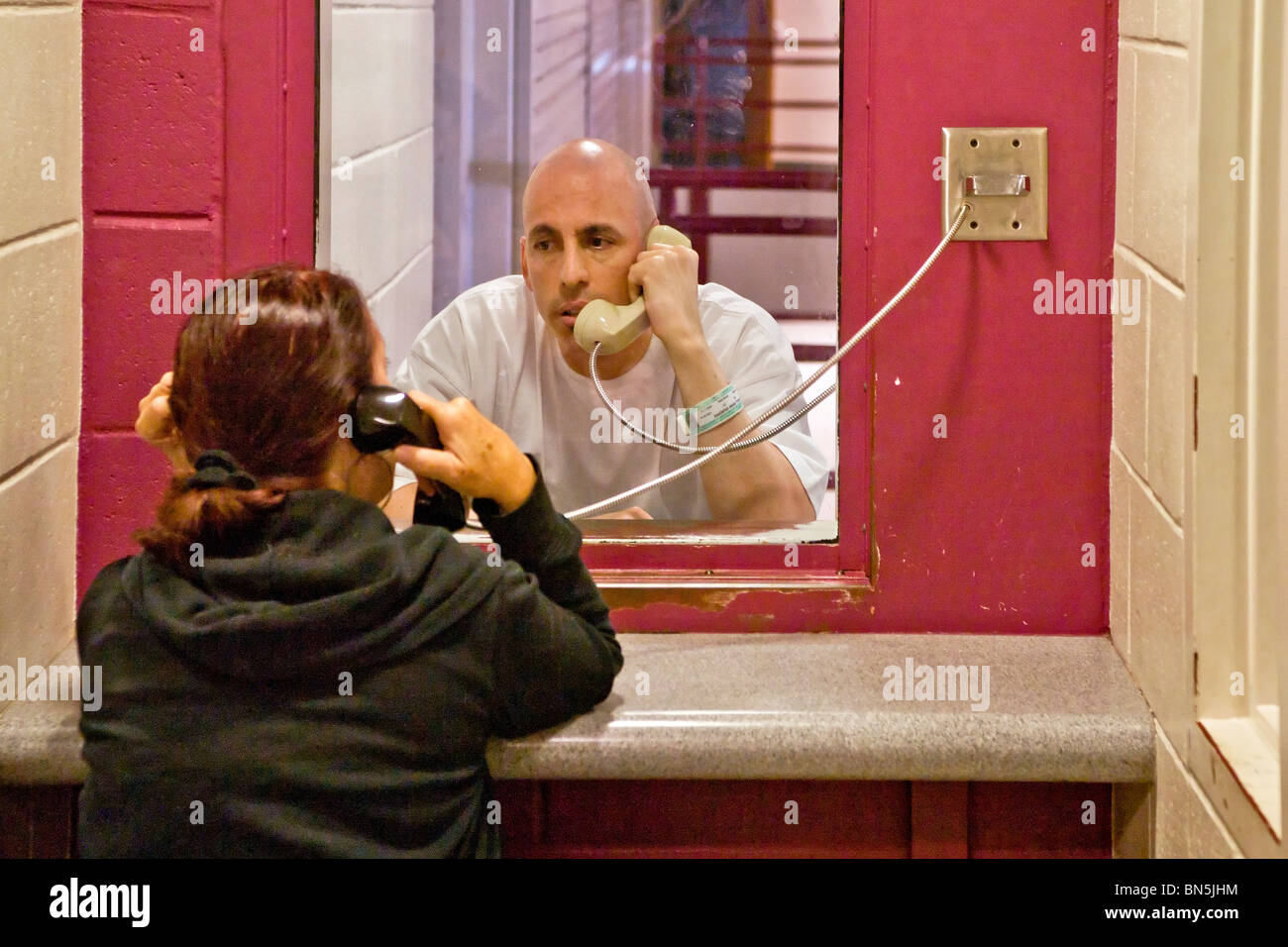 A prisoner talks with his wife using a telephone at the Santa Ana, CA, city jail. Note cell block in background. MODEL RELEASE Stock Photo