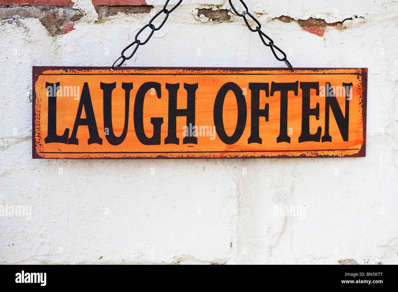 Laugh often. Old metal garden signs on a painted brick wall Stock Photo