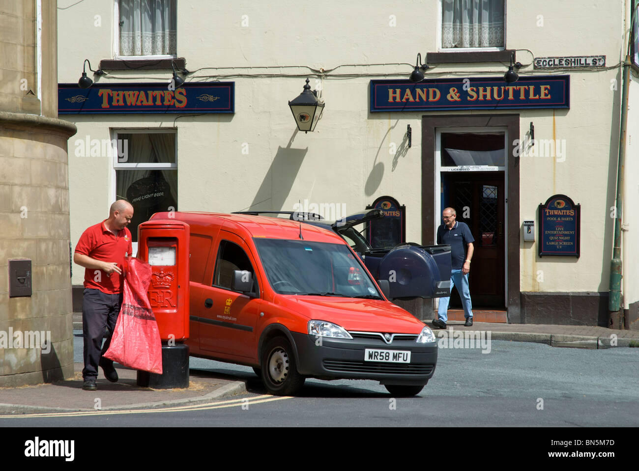 Postman emptying post-box in front of Hand & Shuttle pub, Padiham, Lancashire, England UK Stock Photo