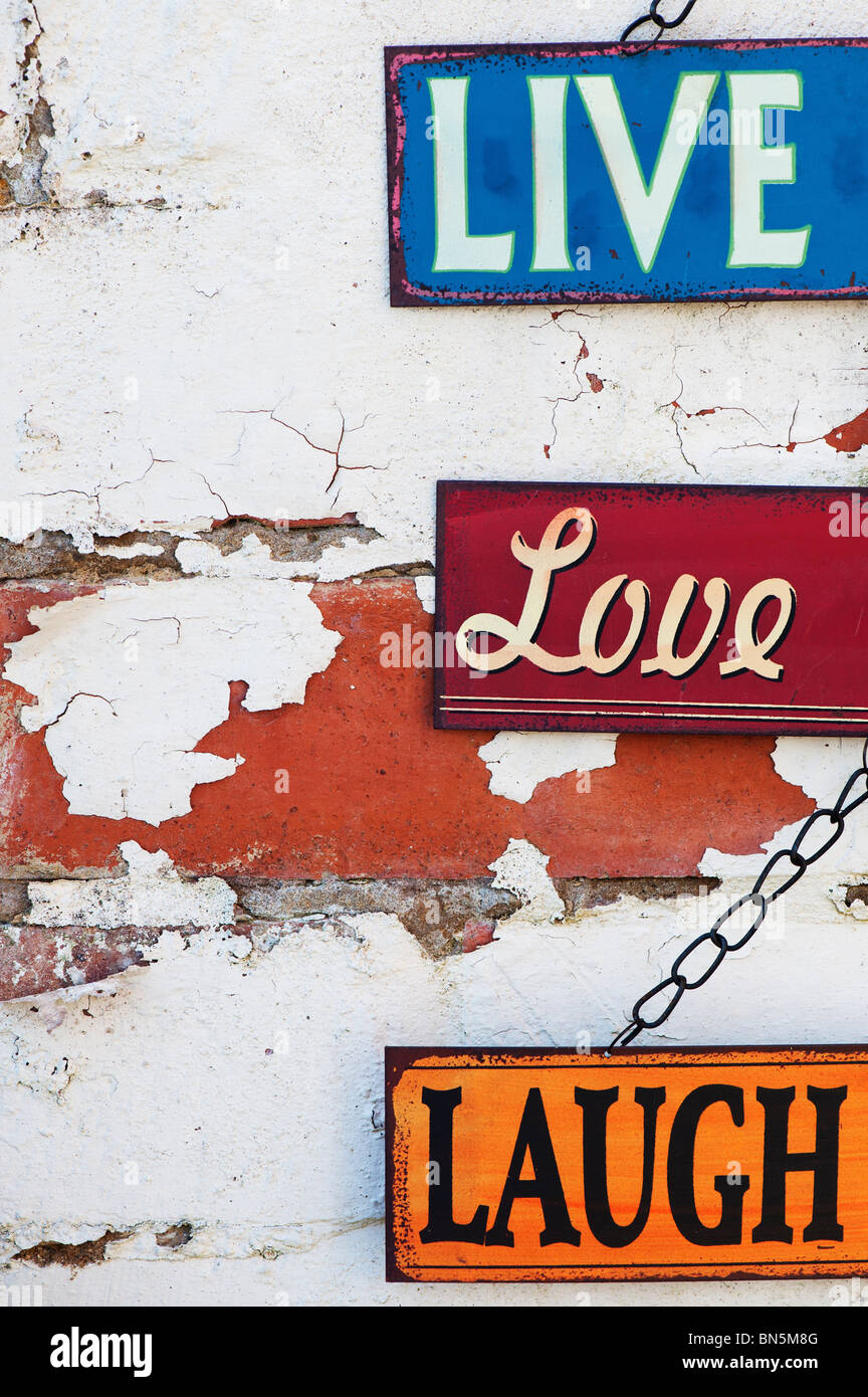 Live, Love, Laugh, old metal garden signs on a painted brick wall Stock Photo