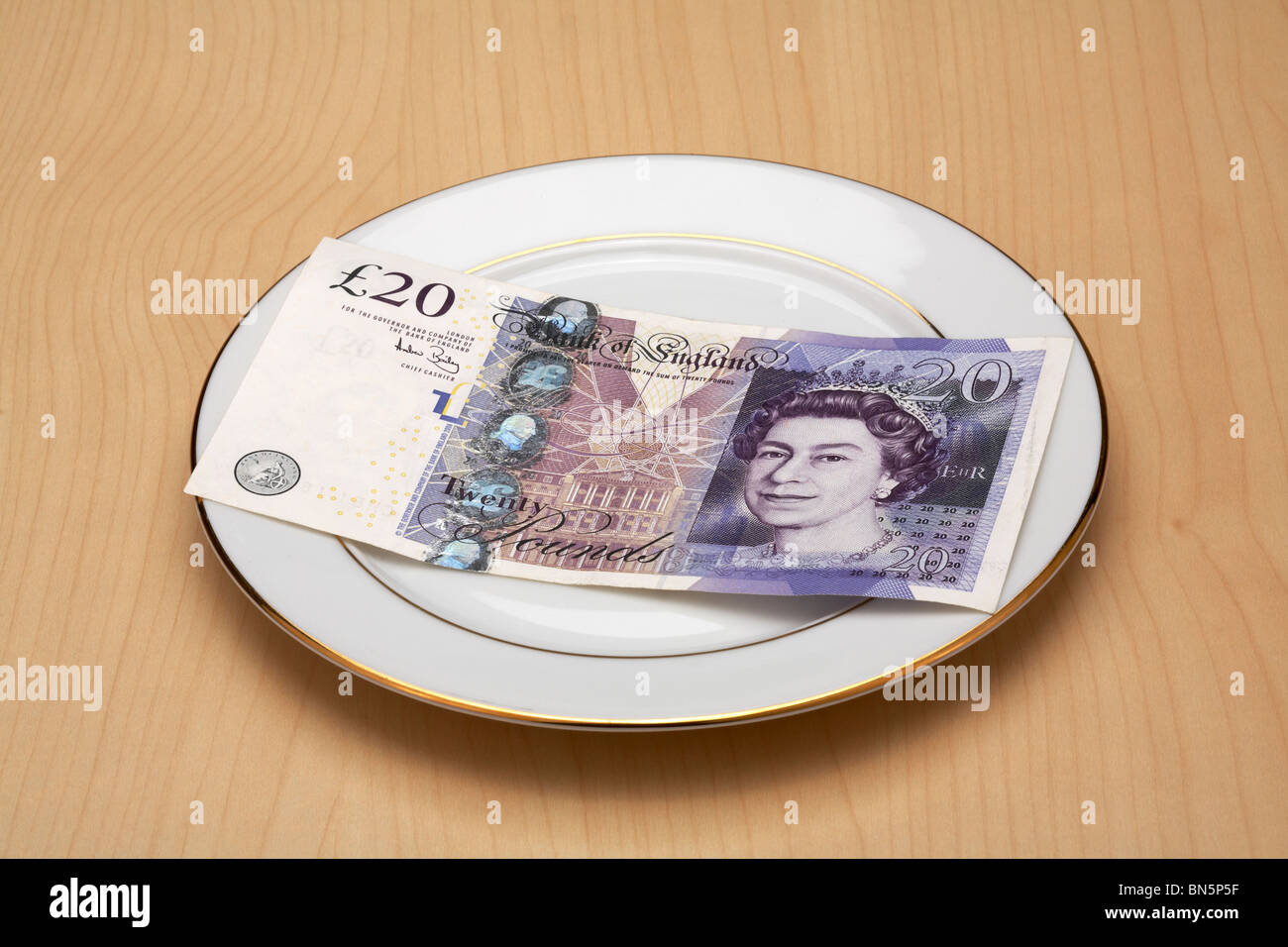 China Plate with UKP £20 Pound Note laying on it Stock Photo