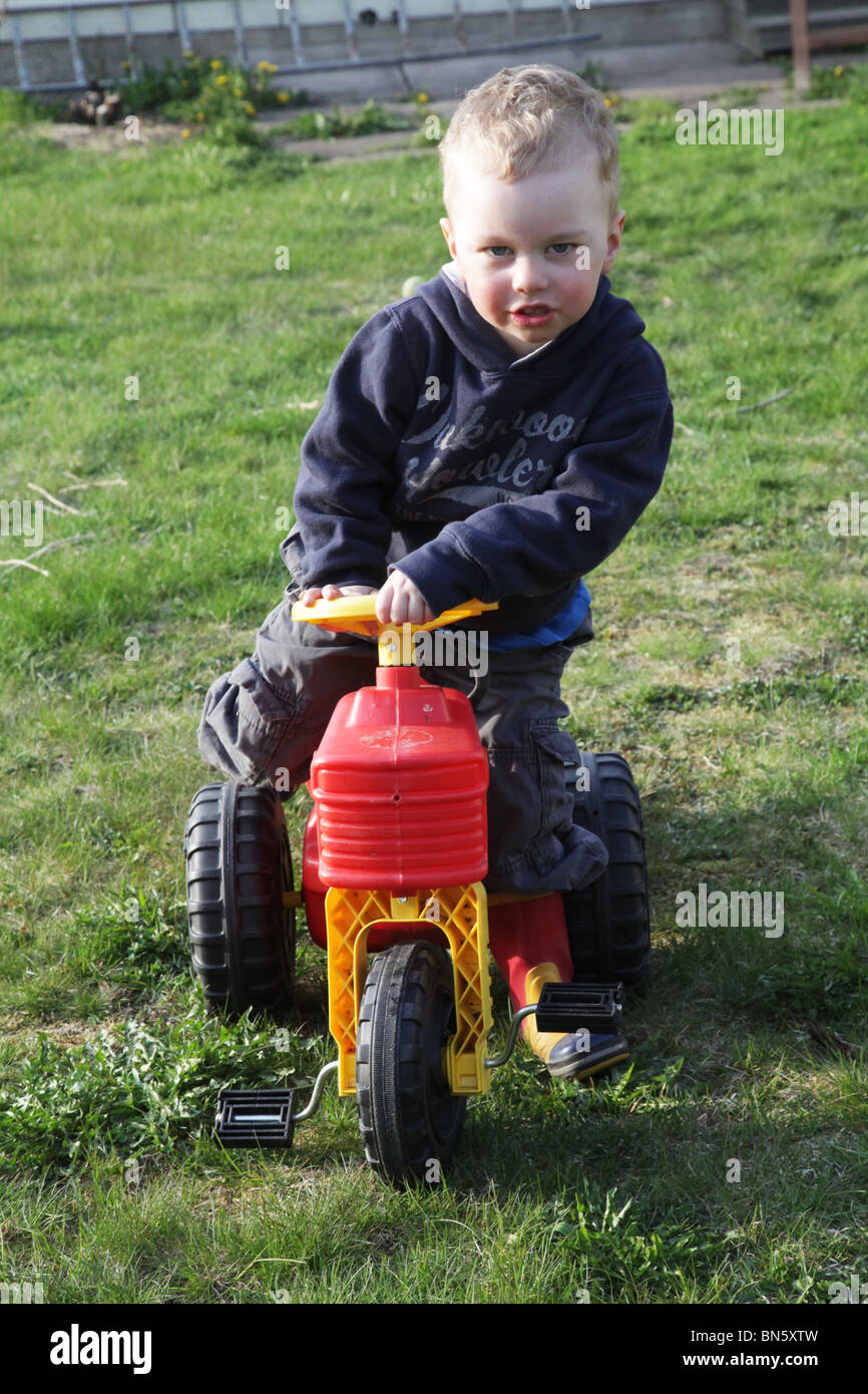 Toddler boy in the garden pretending to be a farmer driving a tractor MODEL RELEASED Stock Photo