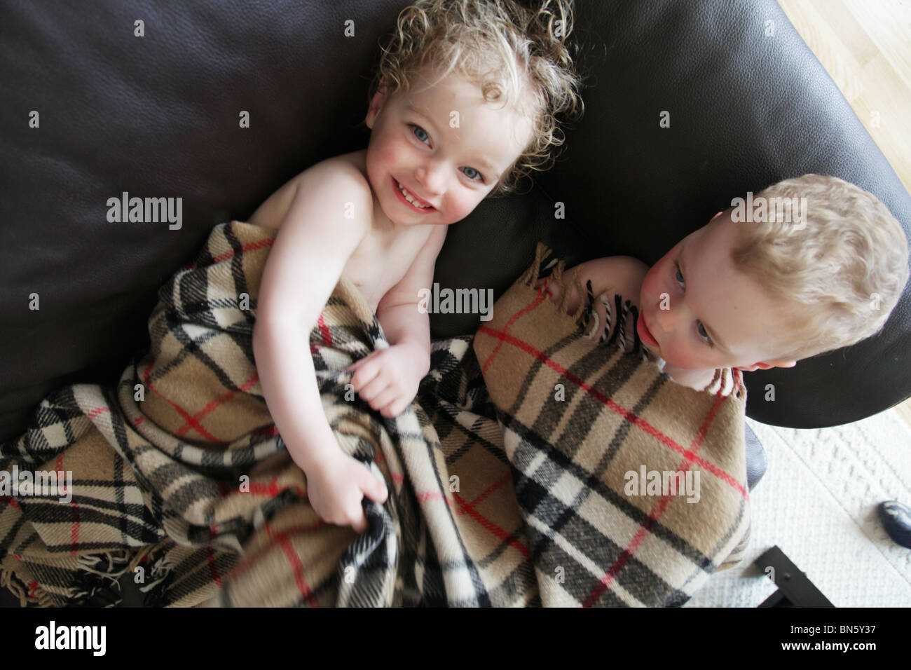 Toddlers siblings brother sister post shower lying on sofa under blanket  family fun MODEL RELEASED Stock Photo - Alamy