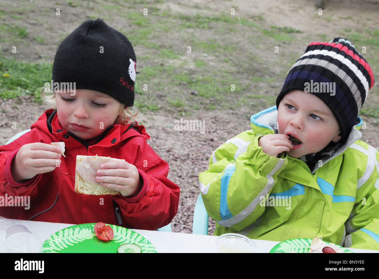Toddlers boy girl siblings sitting at a party table waiting eating sandwiches MODEL RELEASED Stock Photo