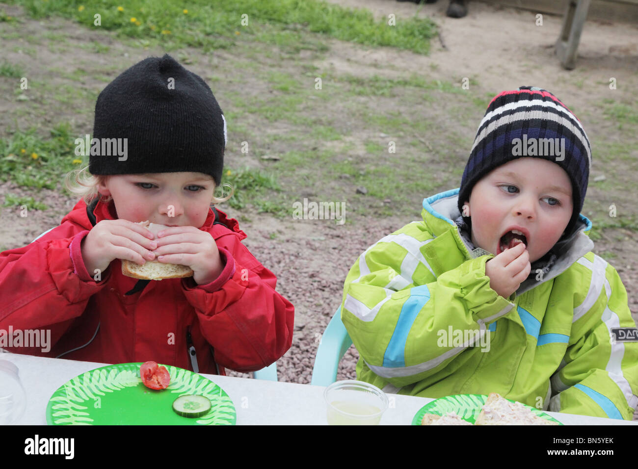 Toddlers boy girl siblings sitting at a party table waiting eating sandwiches MODEL RELEASED Stock Photo