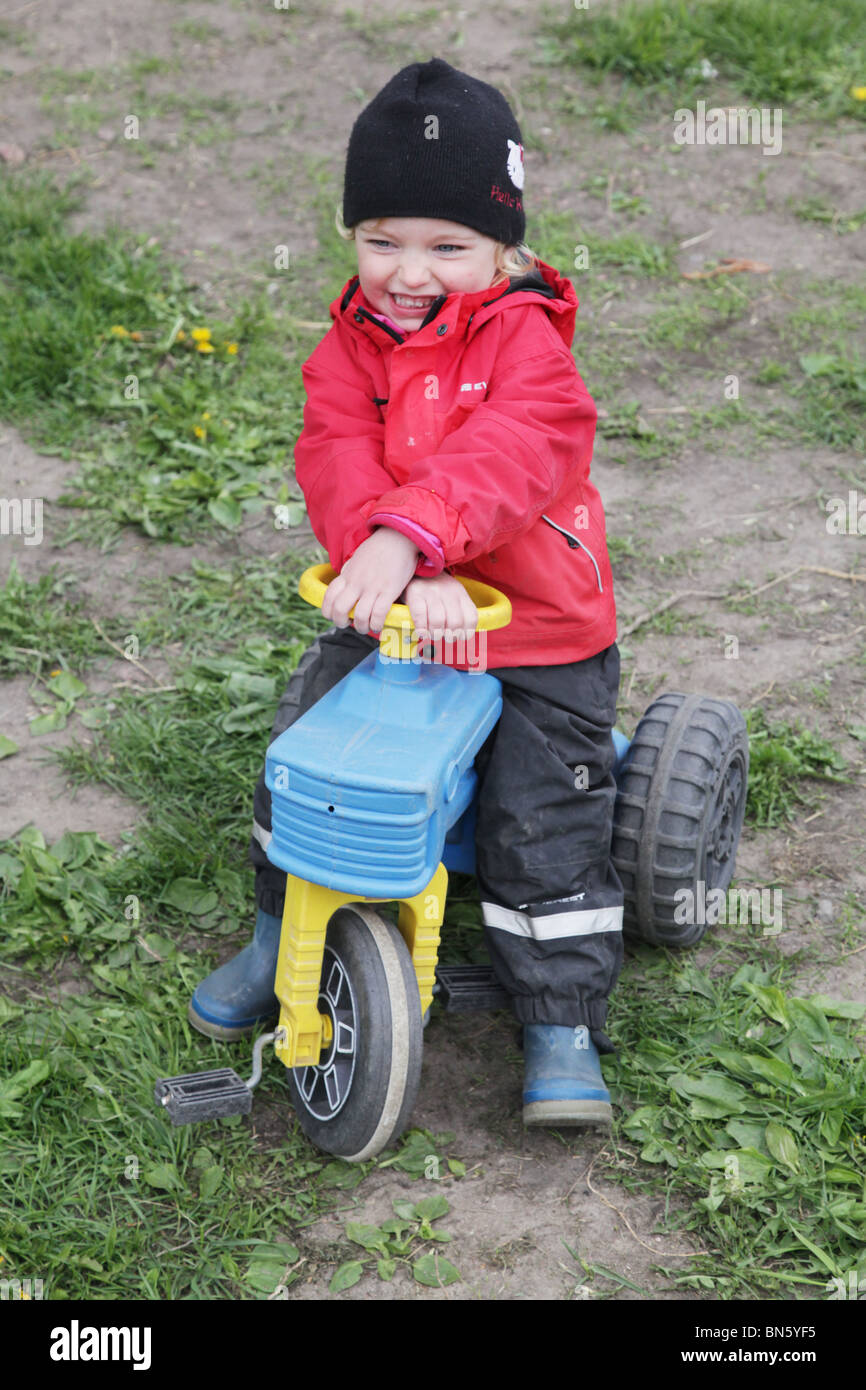 BABY GIRL TODDLER ON PLATIC TRACTOR PLAY PRETEND FARMER FARMING: Toddler girl in nursery pretending to be a farmer with a tractor MODEL RELEASED Stock Photo