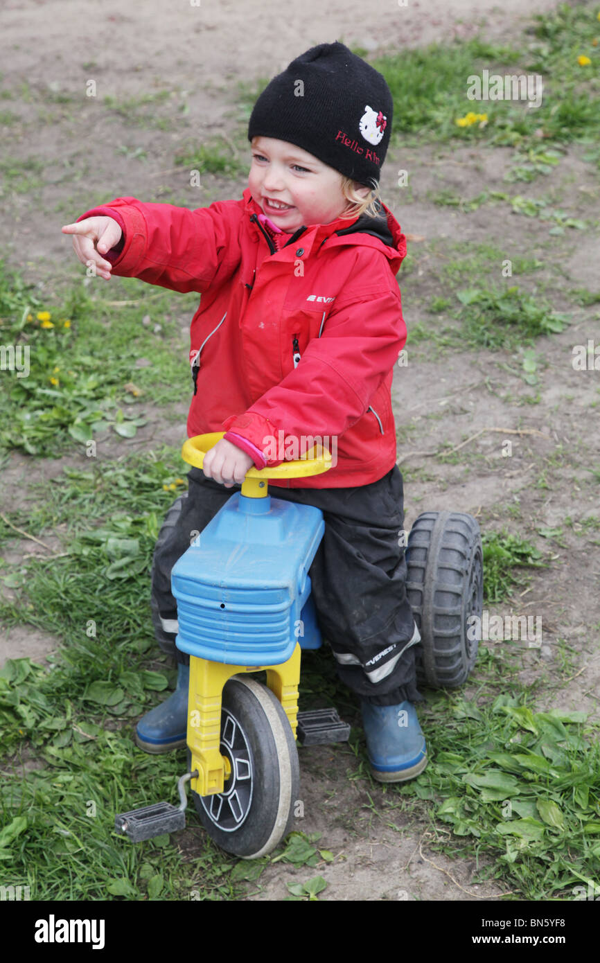 BABY GIRL TODDLER ON PLATIC TRACTOR PLAY PRETEND FARMER FARMING: Toddler girl in nursery pretending to be a farmer with a tractor MODEL RELEASED Stock Photo