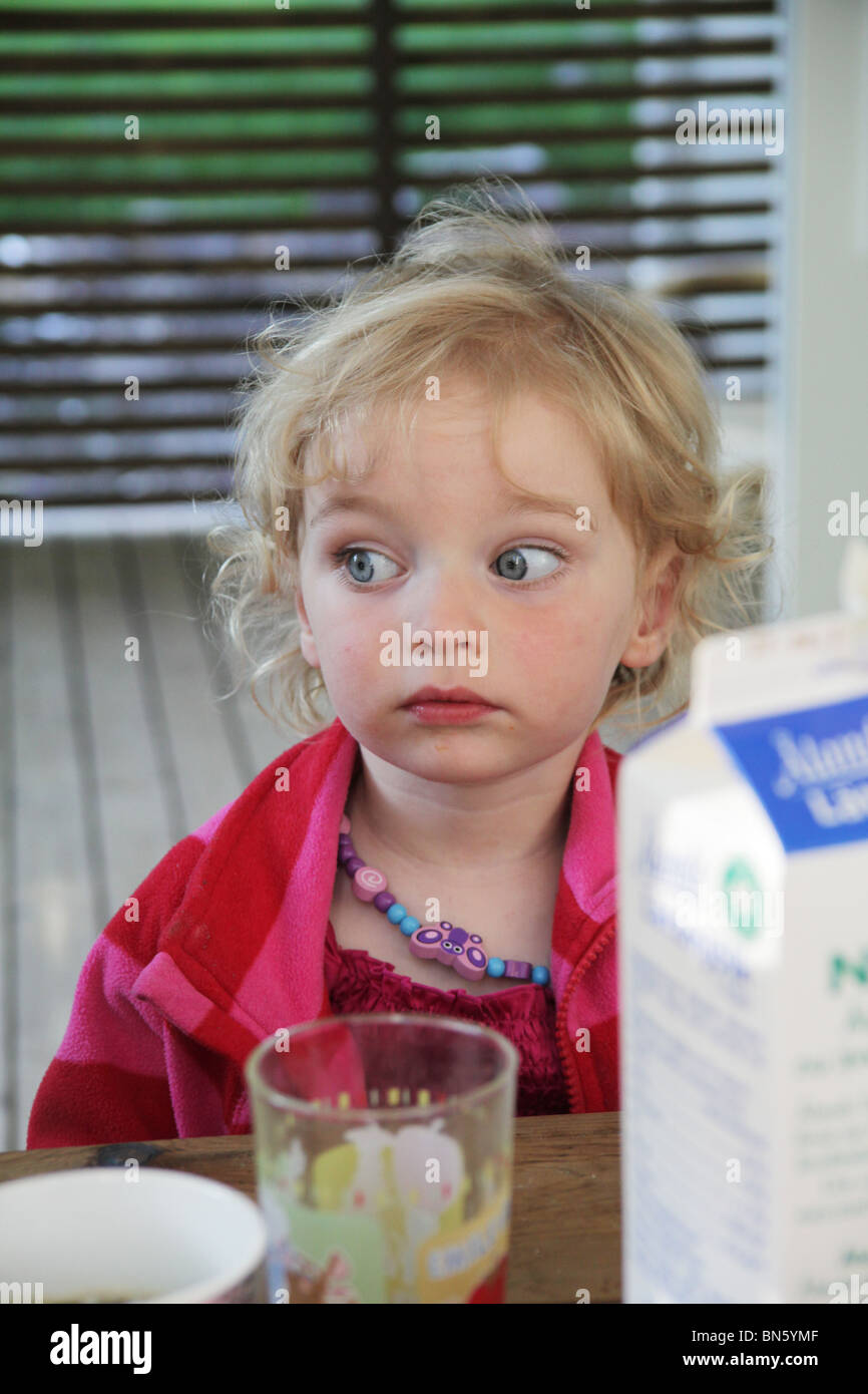 Toddler girl sitting alone at a table waiting for her food MODEL RELEASED Stock Photo