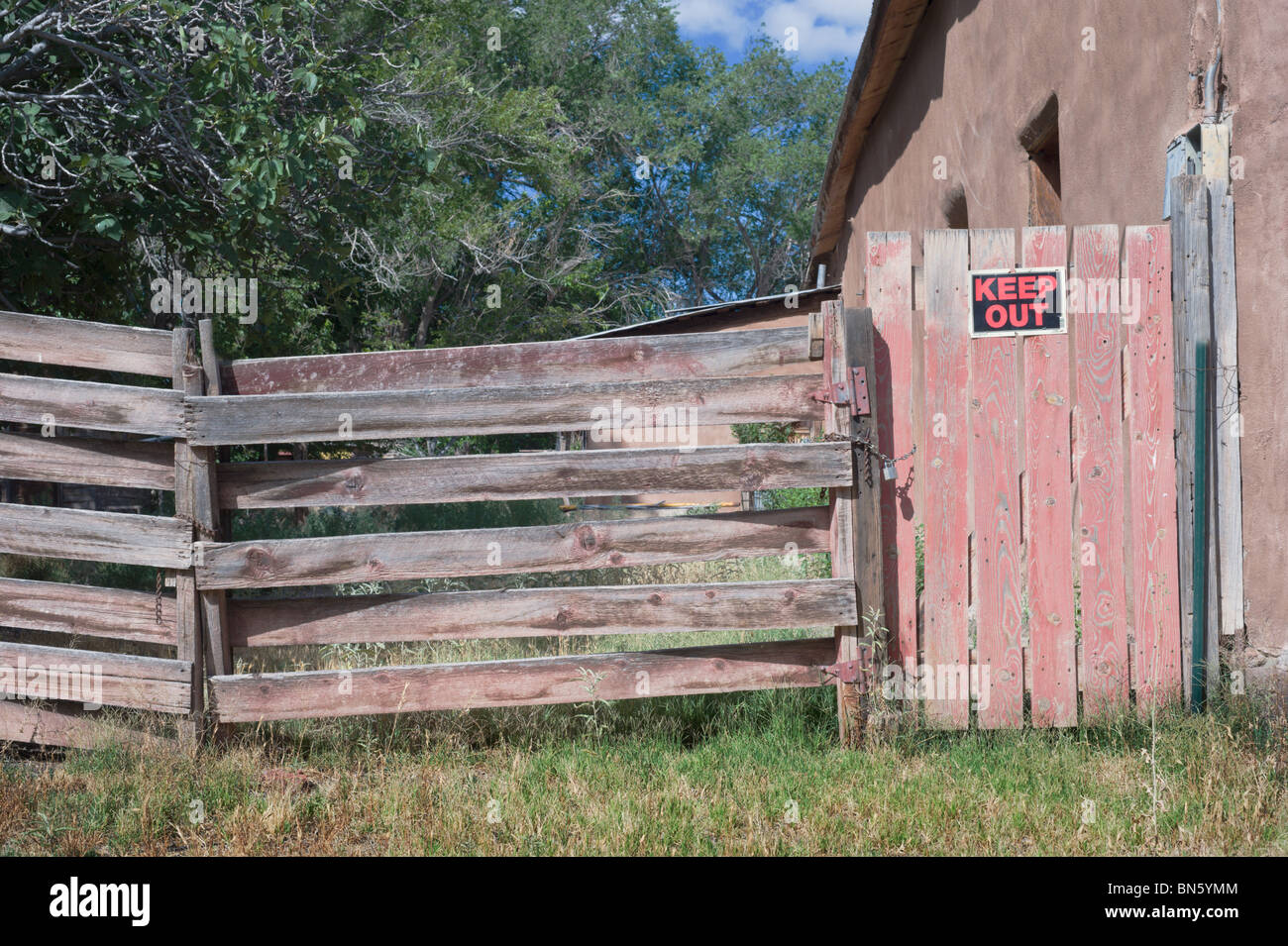 An old weathered wood fence and locked gate, with a 'KEEP OUT' sign posted, found on the side streets of Tularosa, New Mexico. Stock Photo